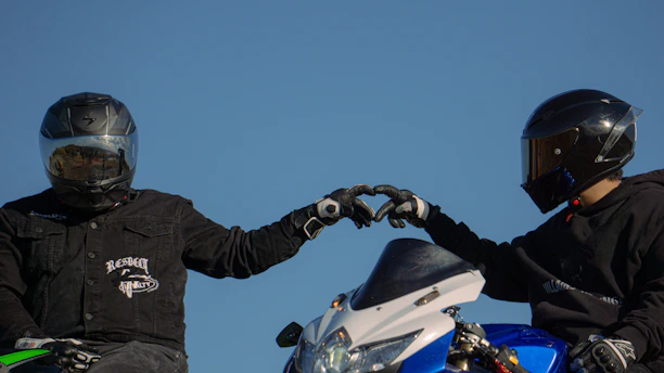 Two people in helmets making a heart shape