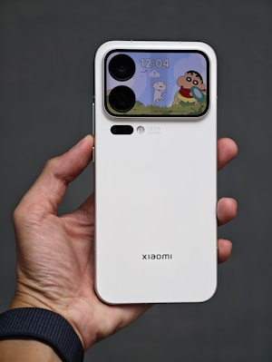 Hand holding white smartphone with cartoon screen