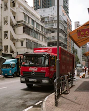 Red coca-cola truck drives down a city street.