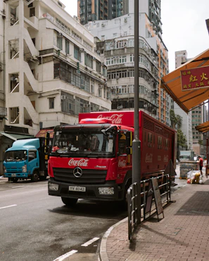 Red coca-cola truck drives down a city street.