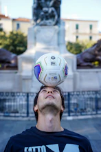 Man balancing soccer ball on his head outdoors