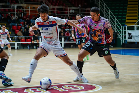Two men playing indoor soccer on a court.