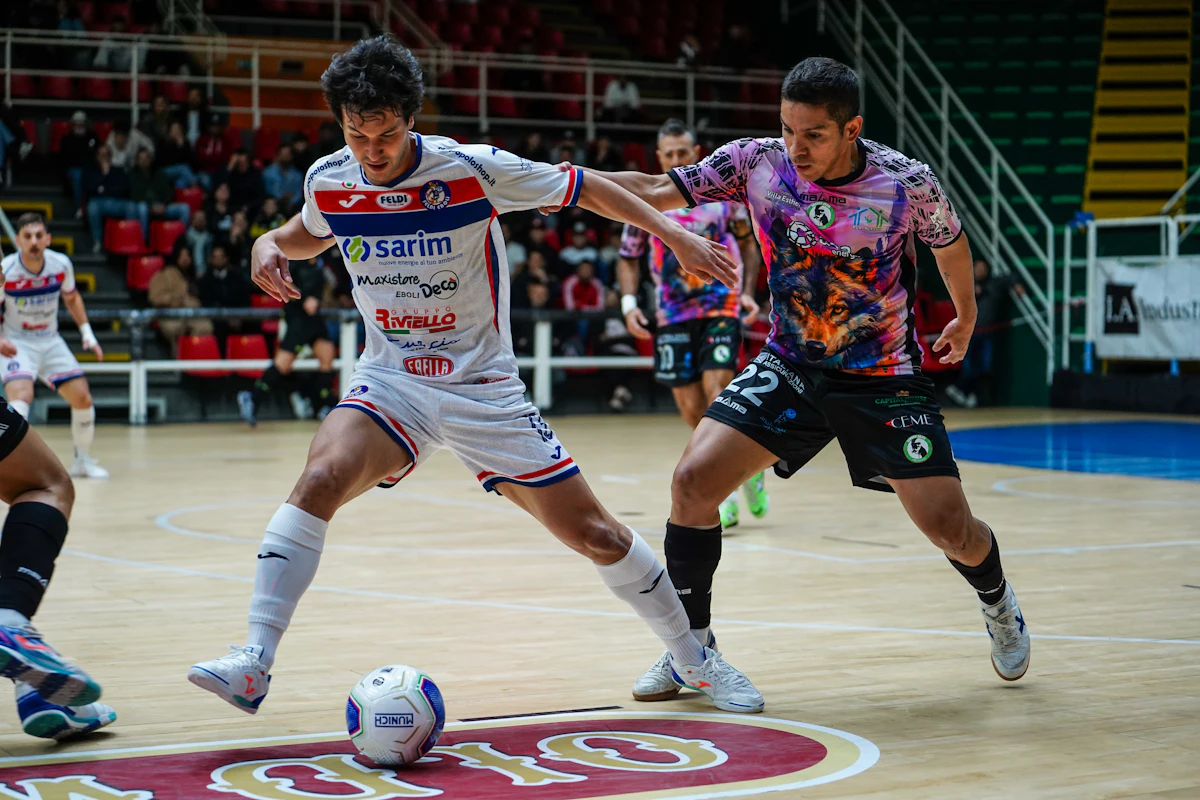 Dua pemain futsal berebut bola di lapangan indoor