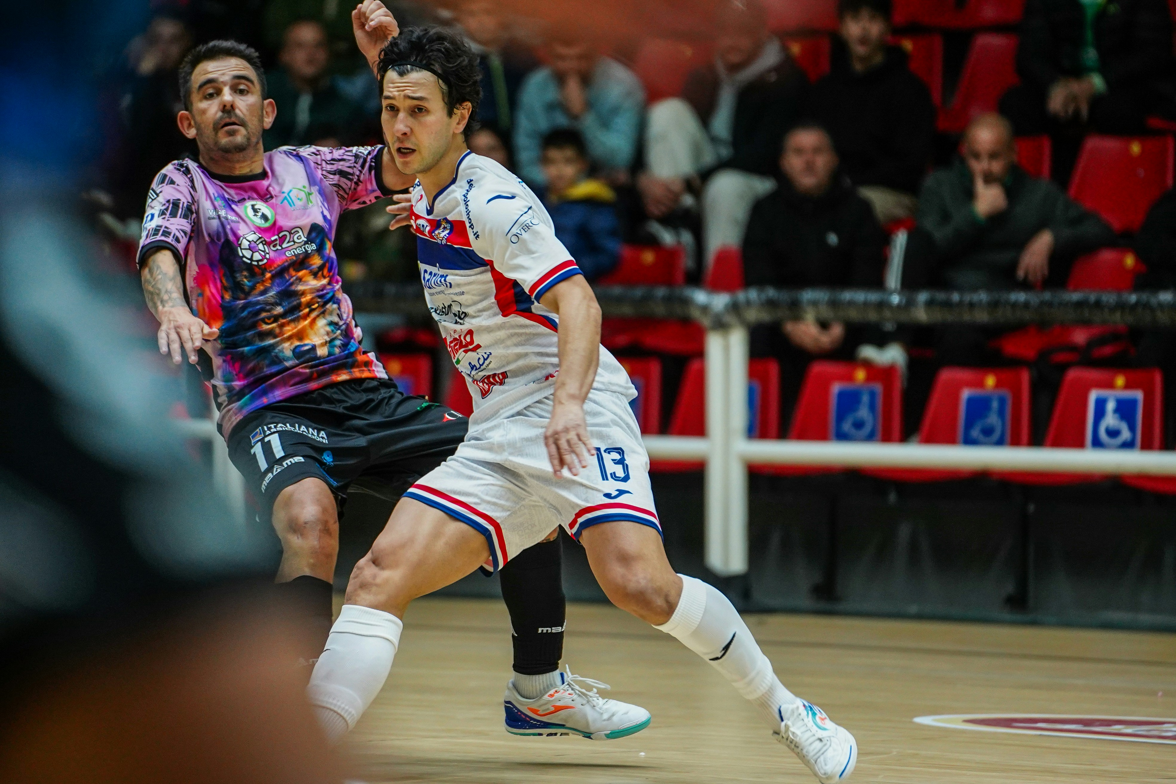 Two male athletes playing indoor soccer on a court.