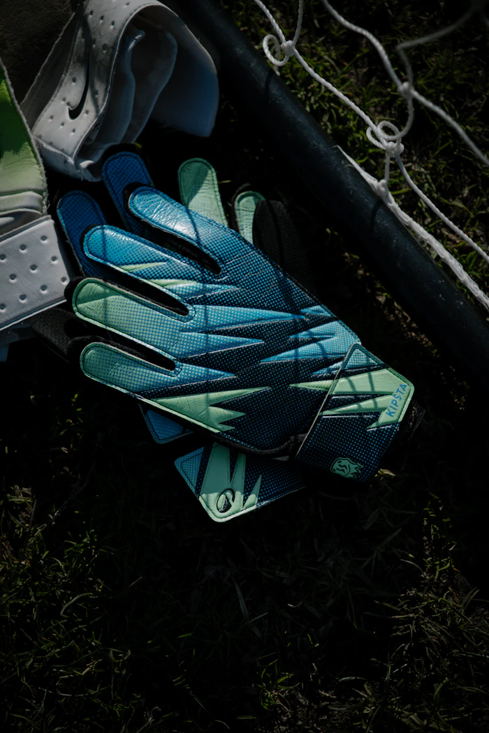 Goalkeeper gloves resting on grass near a net