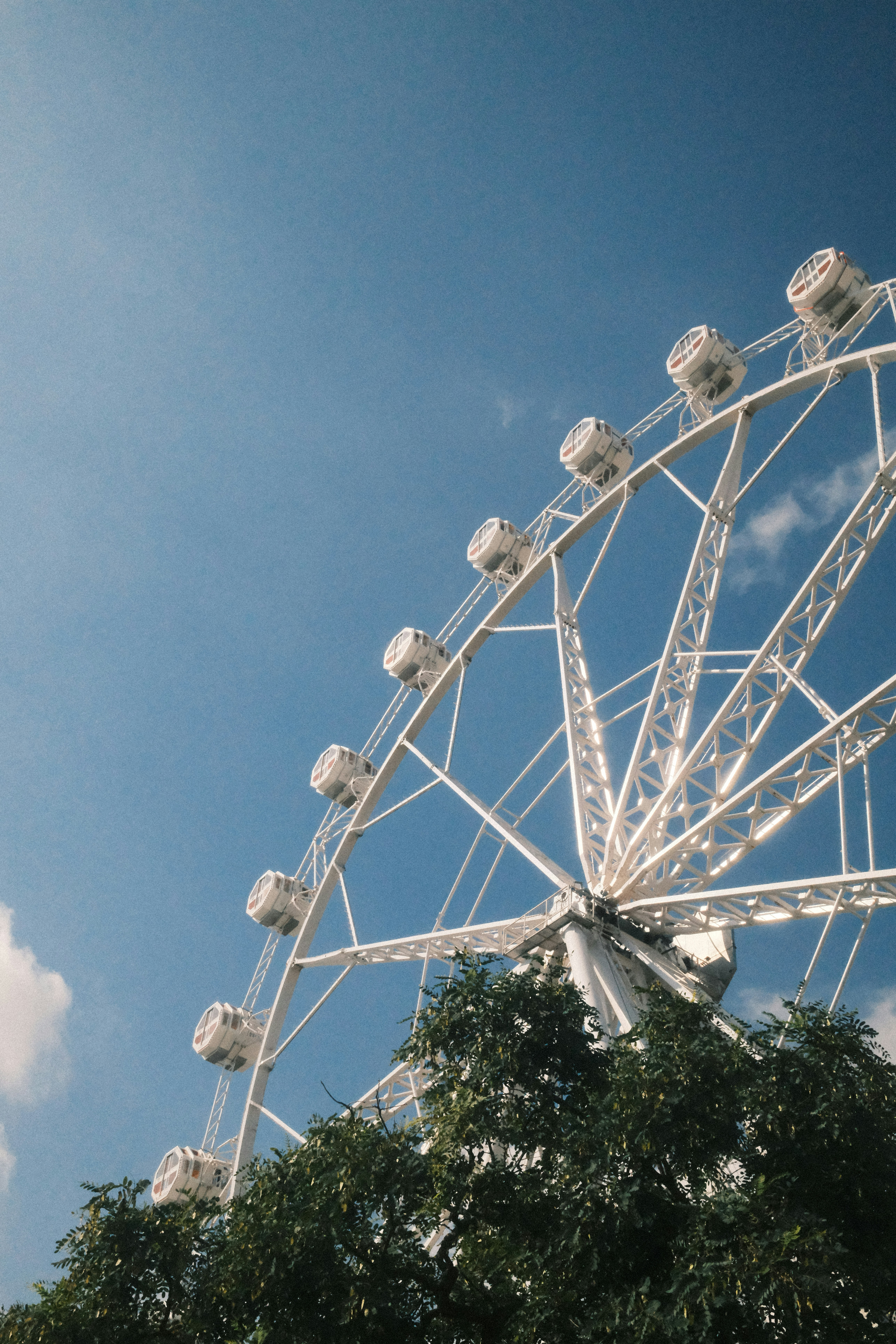A white ferris wheel against a clear blue sky.