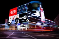 Busy cityscape with illuminated billboards and light trails at night