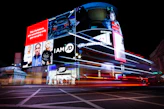 Busy cityscape with illuminated billboards and light trails at night