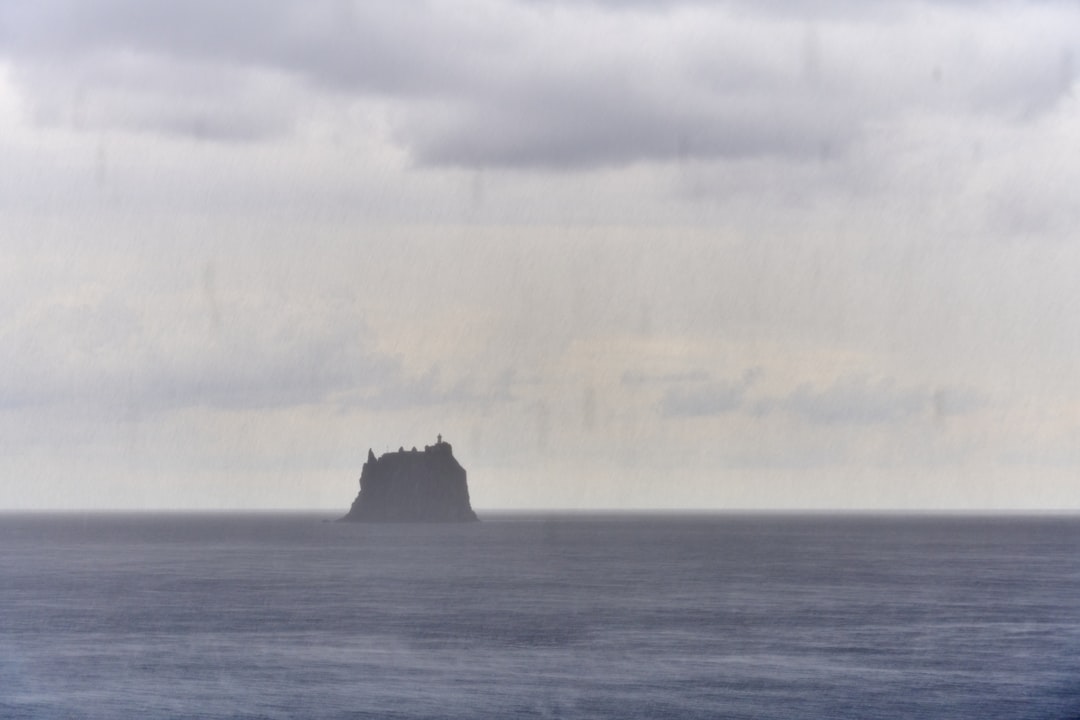 A lone island in the ocean under cloudy sky