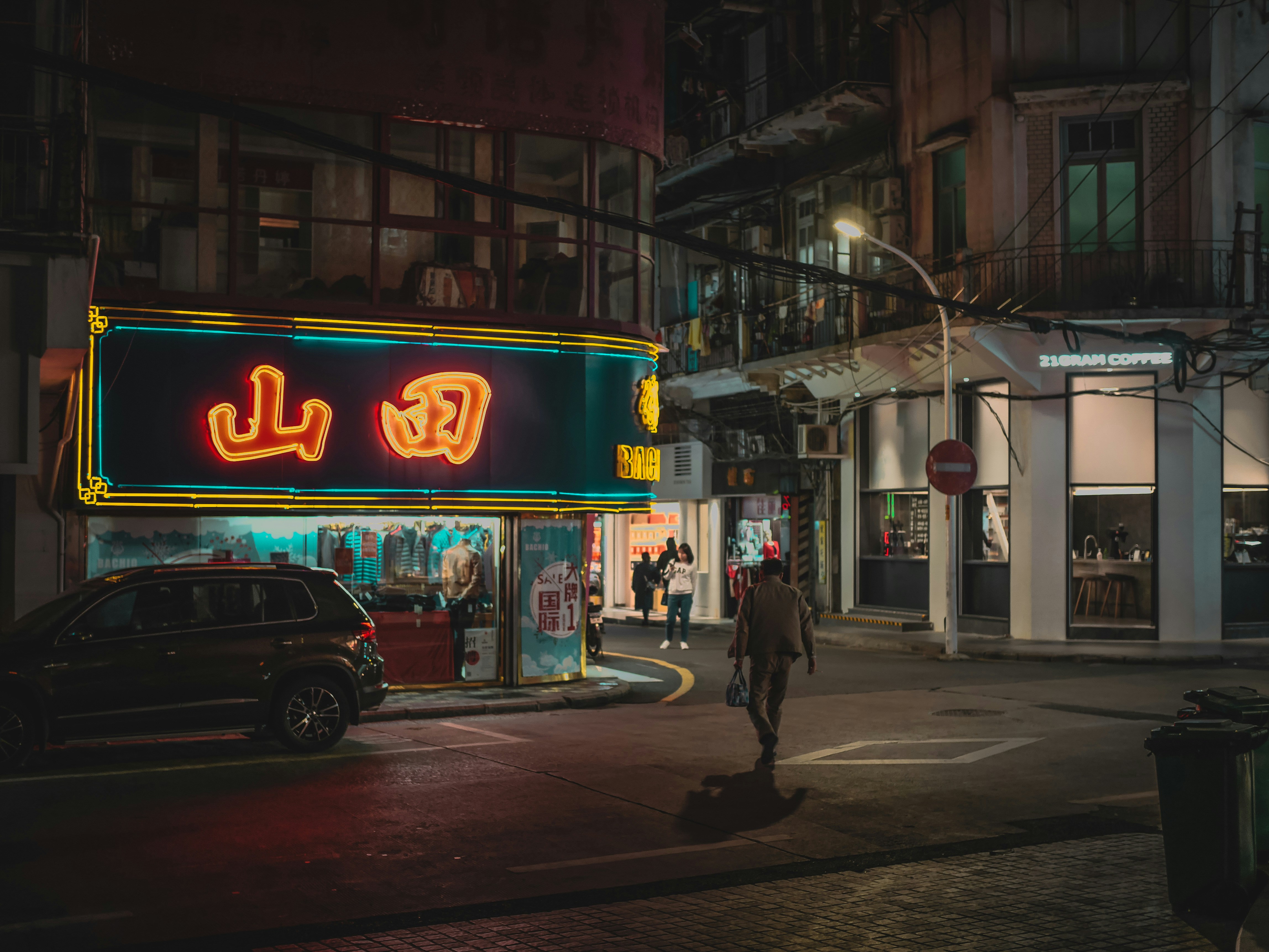 Neon signs illuminate a city street at night.