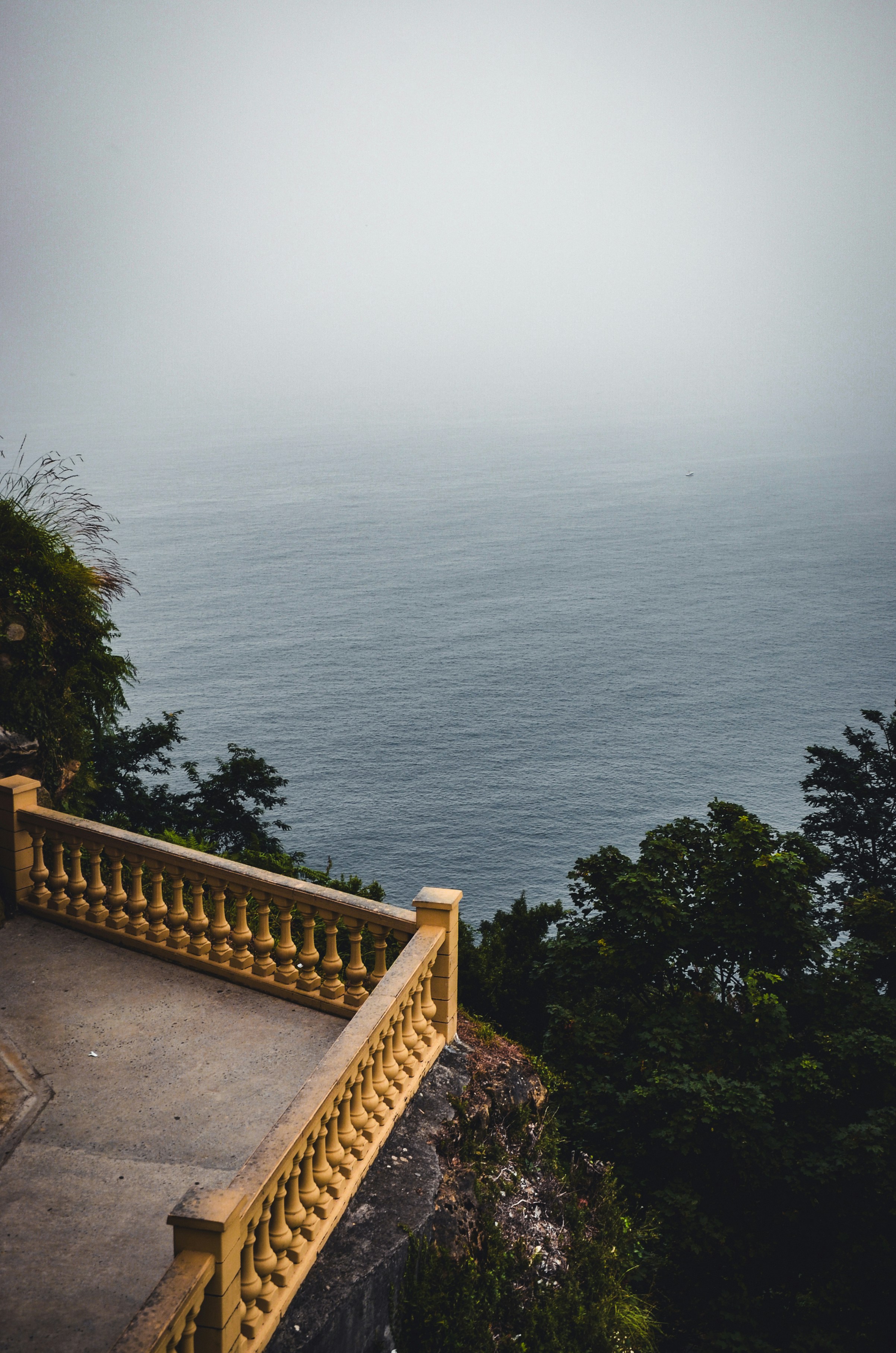 Balcony overlooking a foggy ocean and lush green trees.