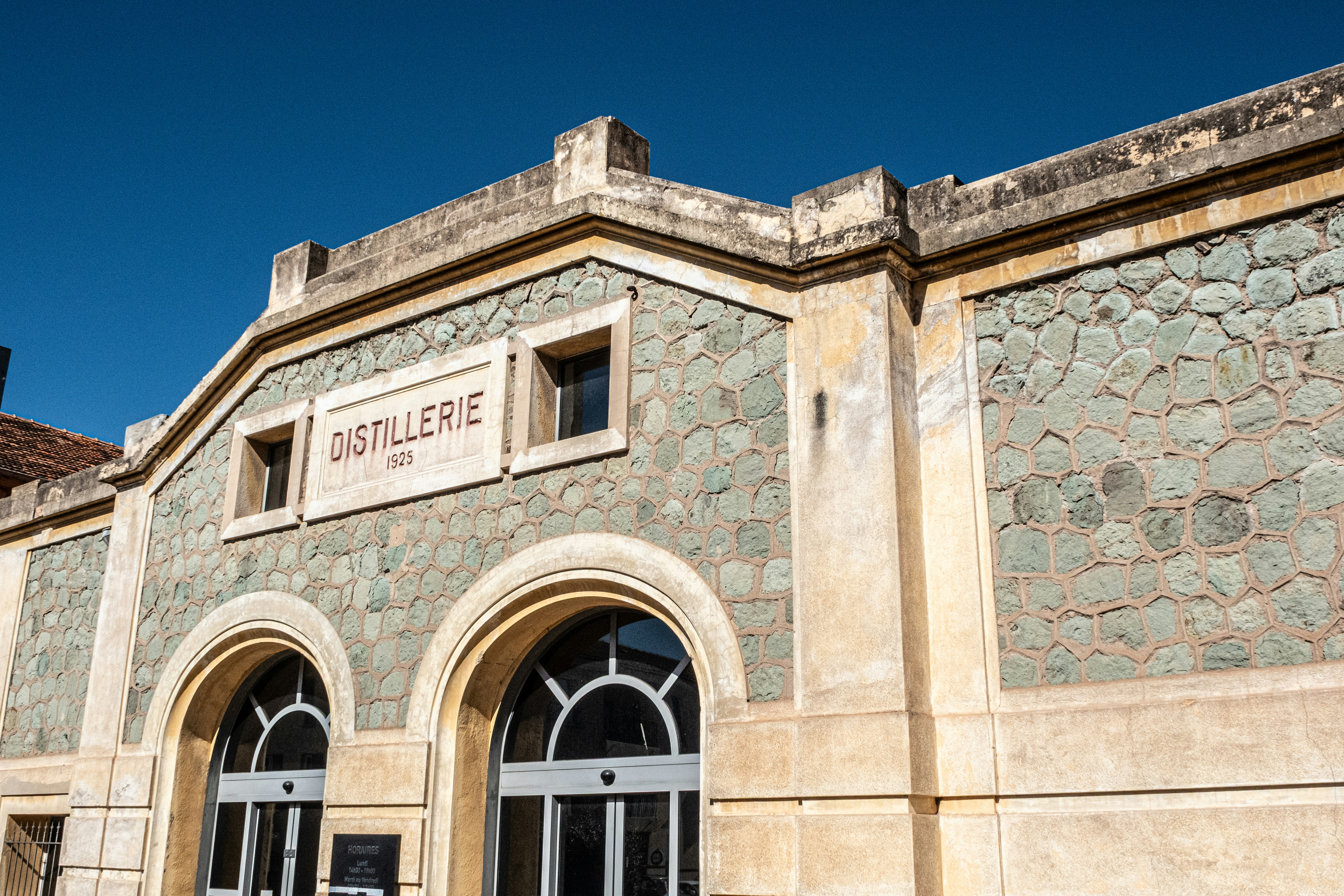 Distillery building with arched entrances under blue sky