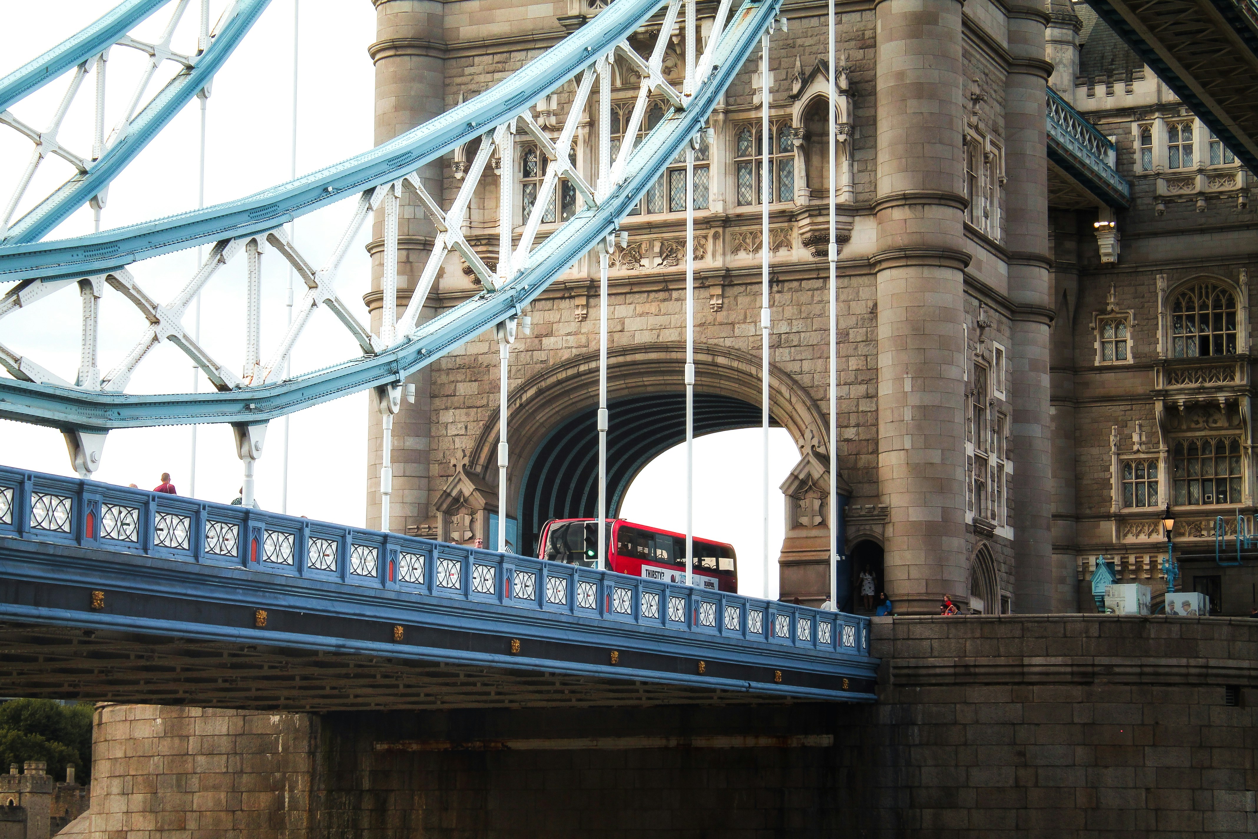 Red double-decker bus crossing tower bridge, london