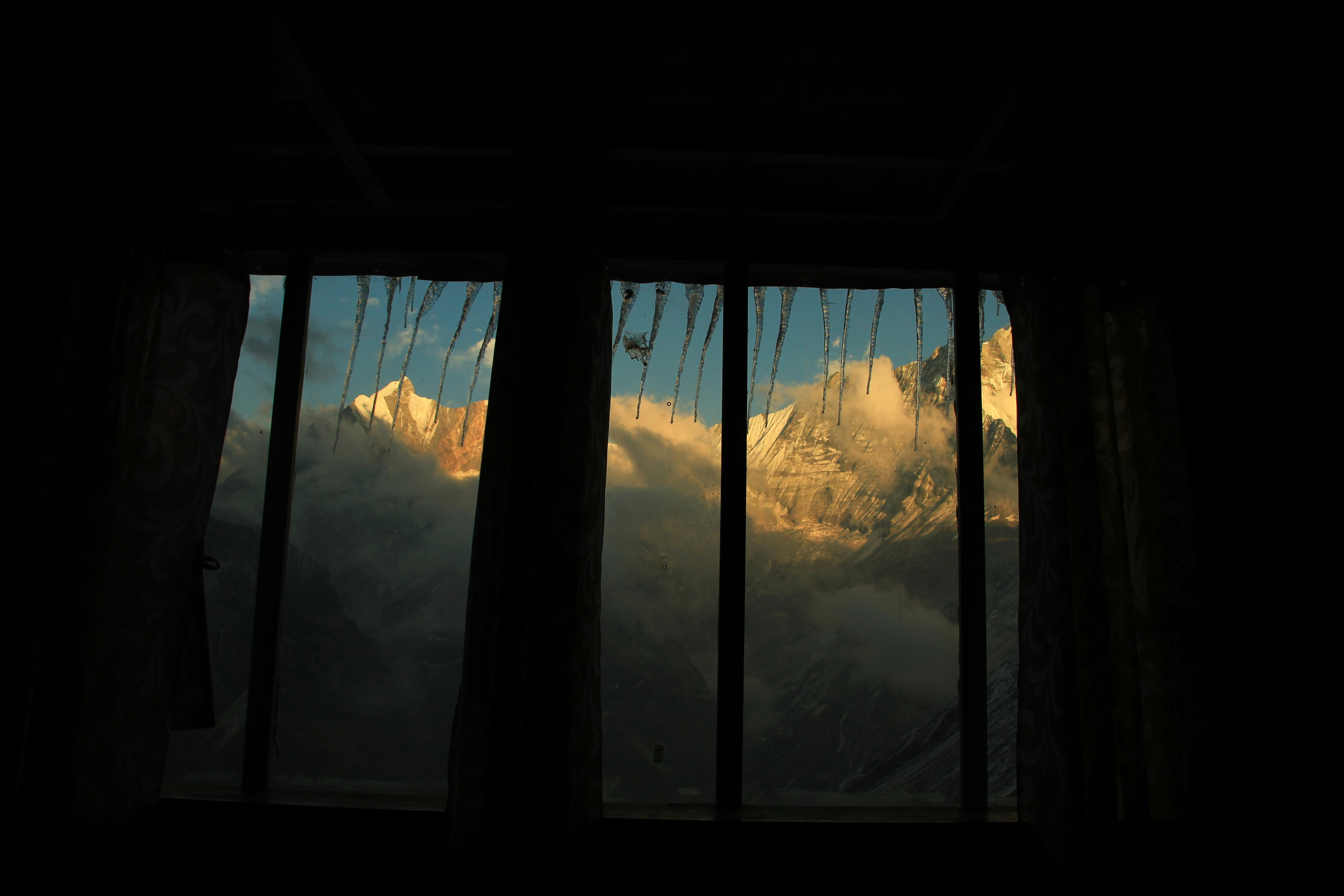 Schneebedeckte Berge, die bei Sonnenuntergang durch ein Fenster zu sehen sind.