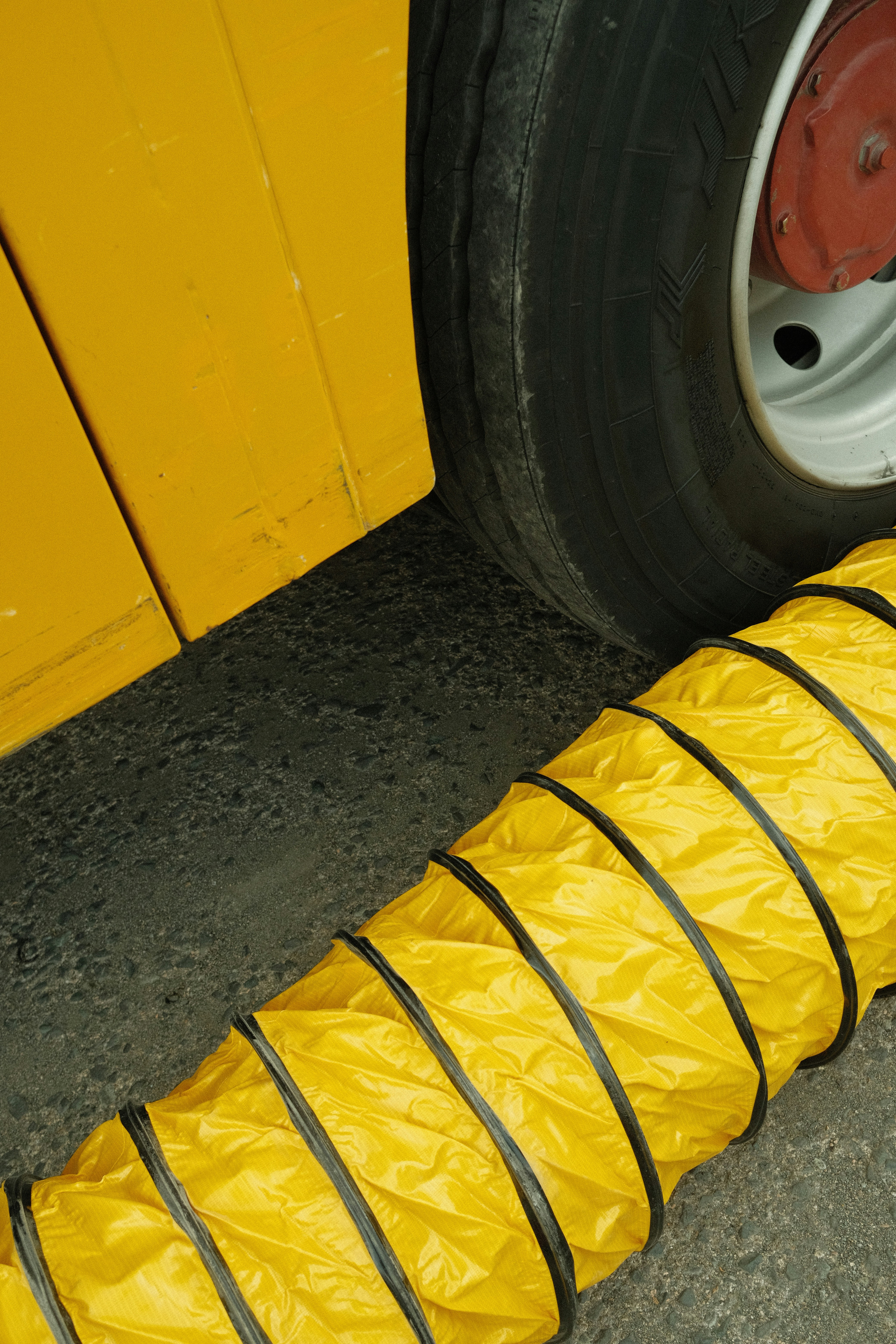 Yellow flexible ducting next to a large tire