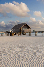 Thatched roof hut on stilts over calm water