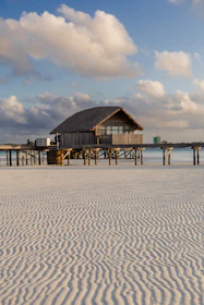 Thatched roof hut on stilts over calm water
