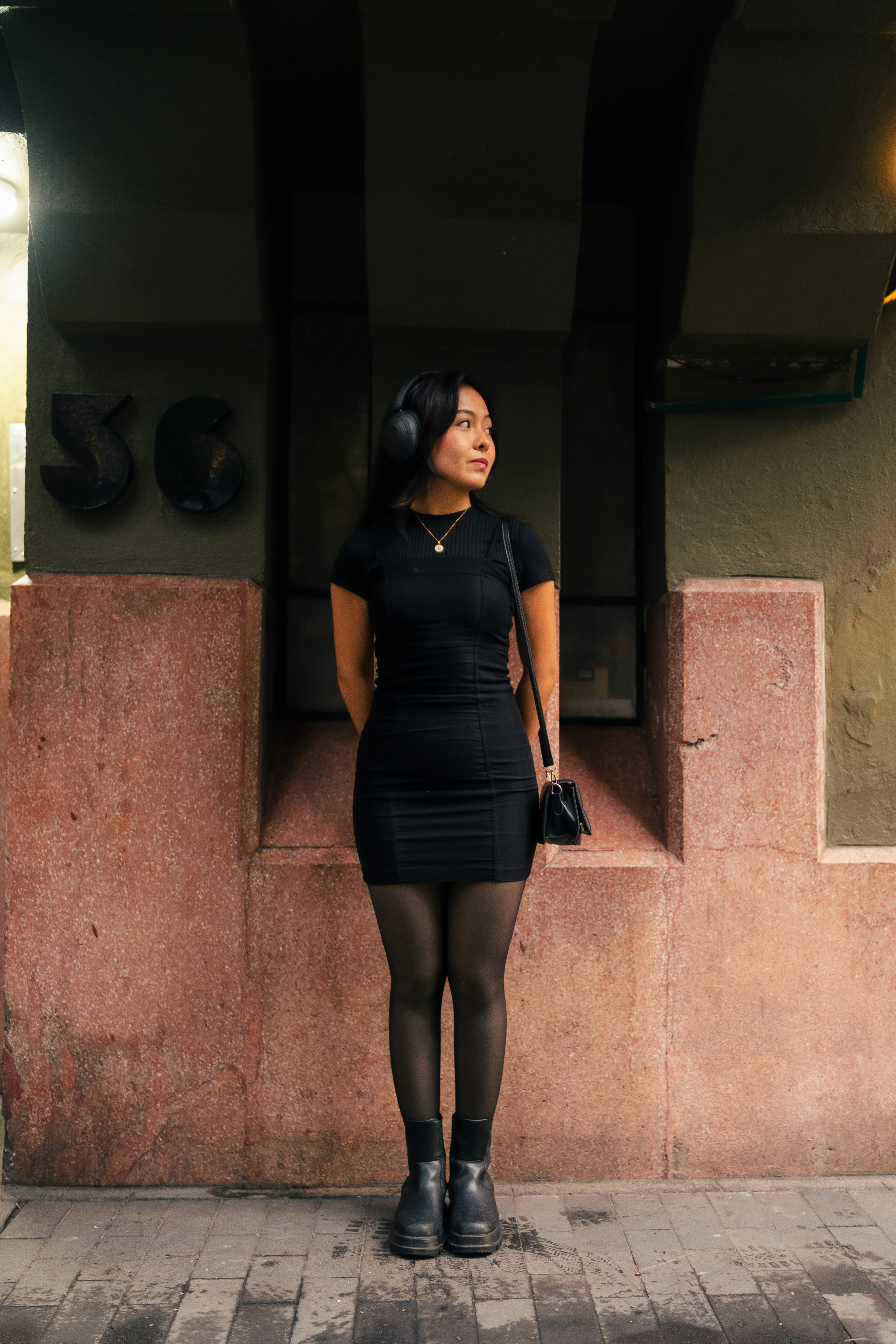 Woman in black dress wearing headphones outdoors