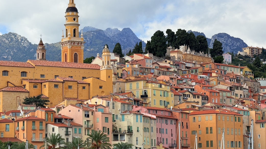 Colorful buildings on a hillside with mountains behind.