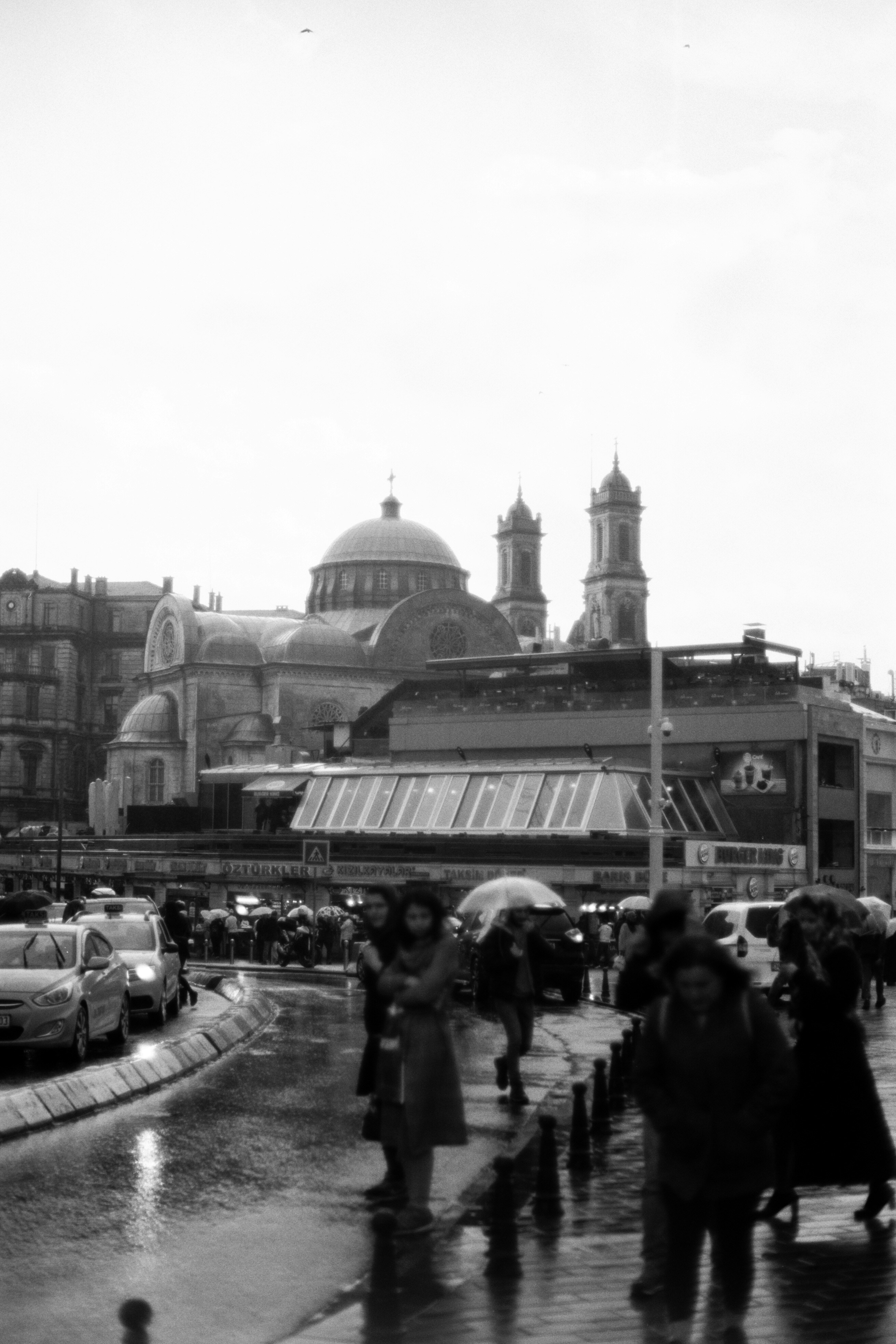 People with umbrellas walk on a wet city street.
