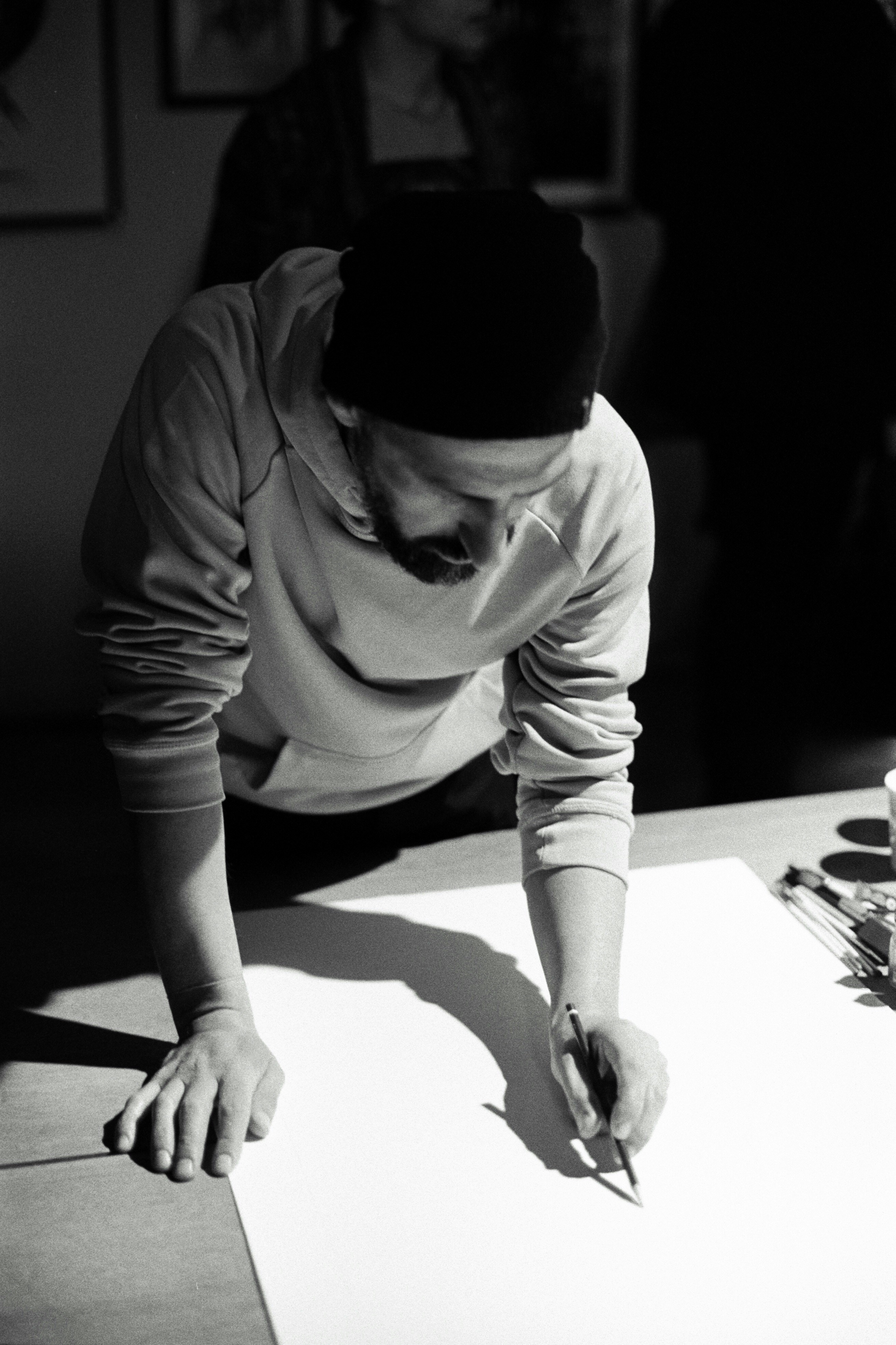 Artist drawing on paper in a studio.