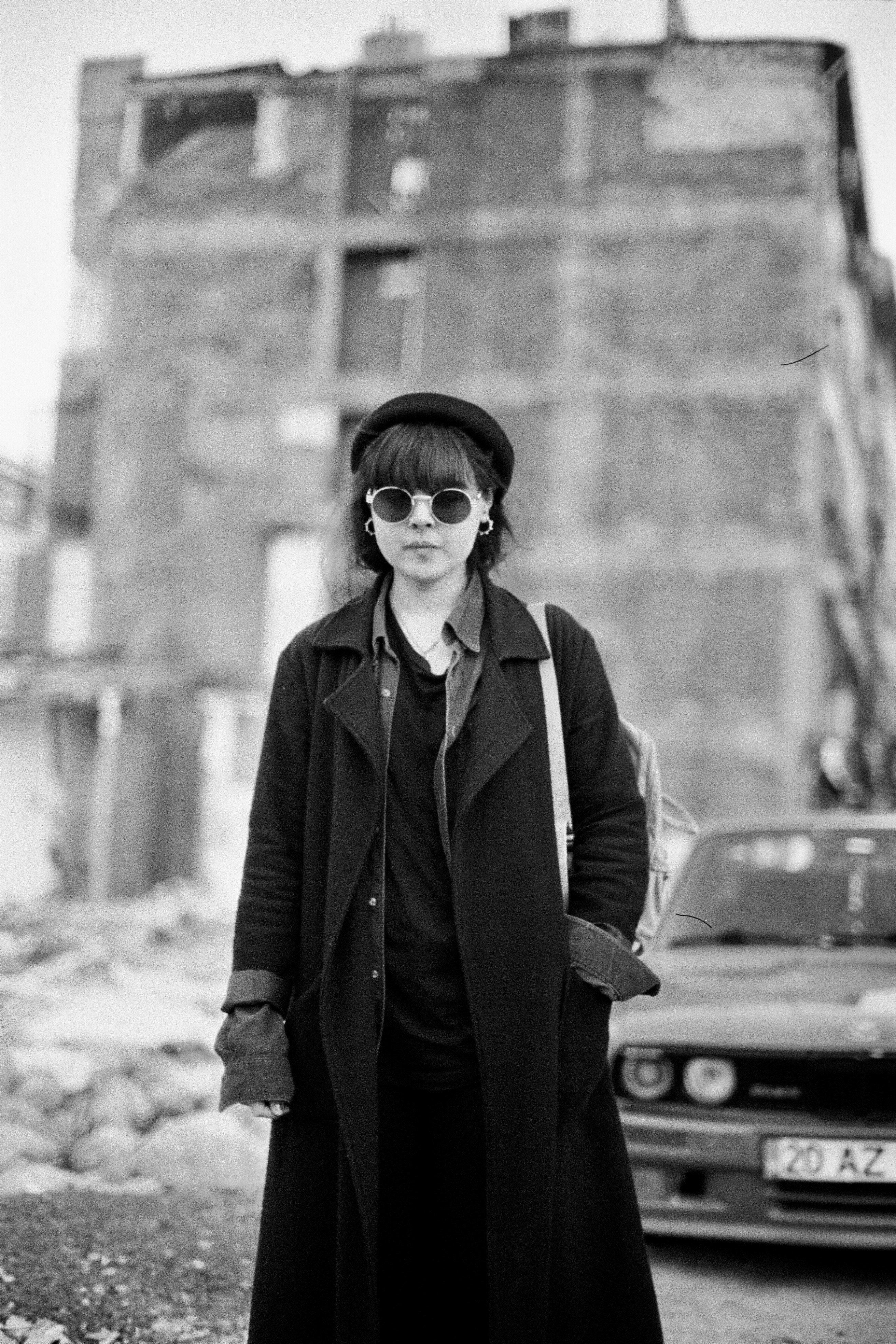 Woman in hat and sunglasses with building background