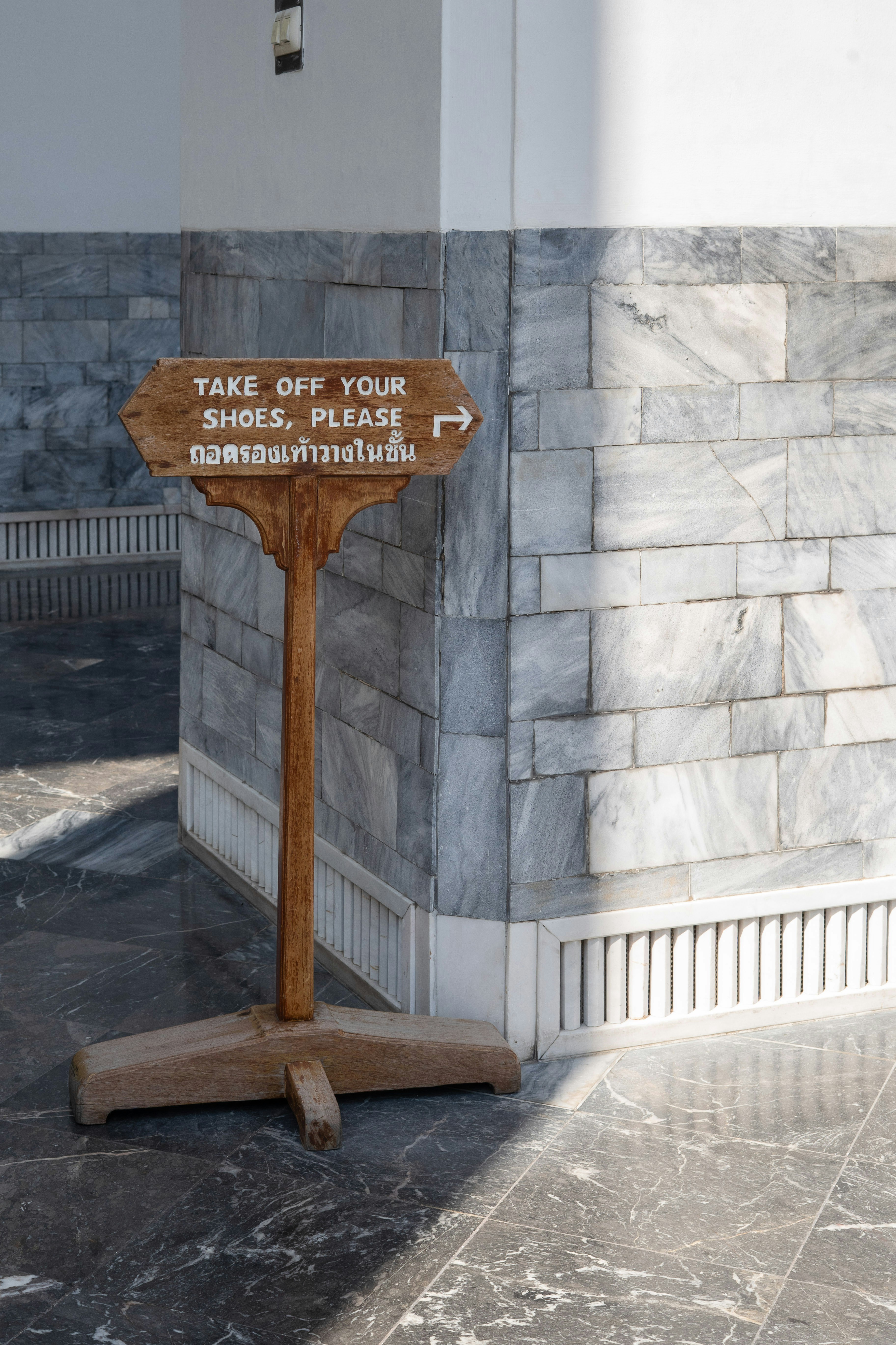 Holzschild mit der Aufforderung, die Schuhe auszuziehen