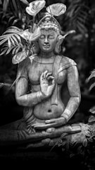 Stone buddha statue surrounded by lush green foliage