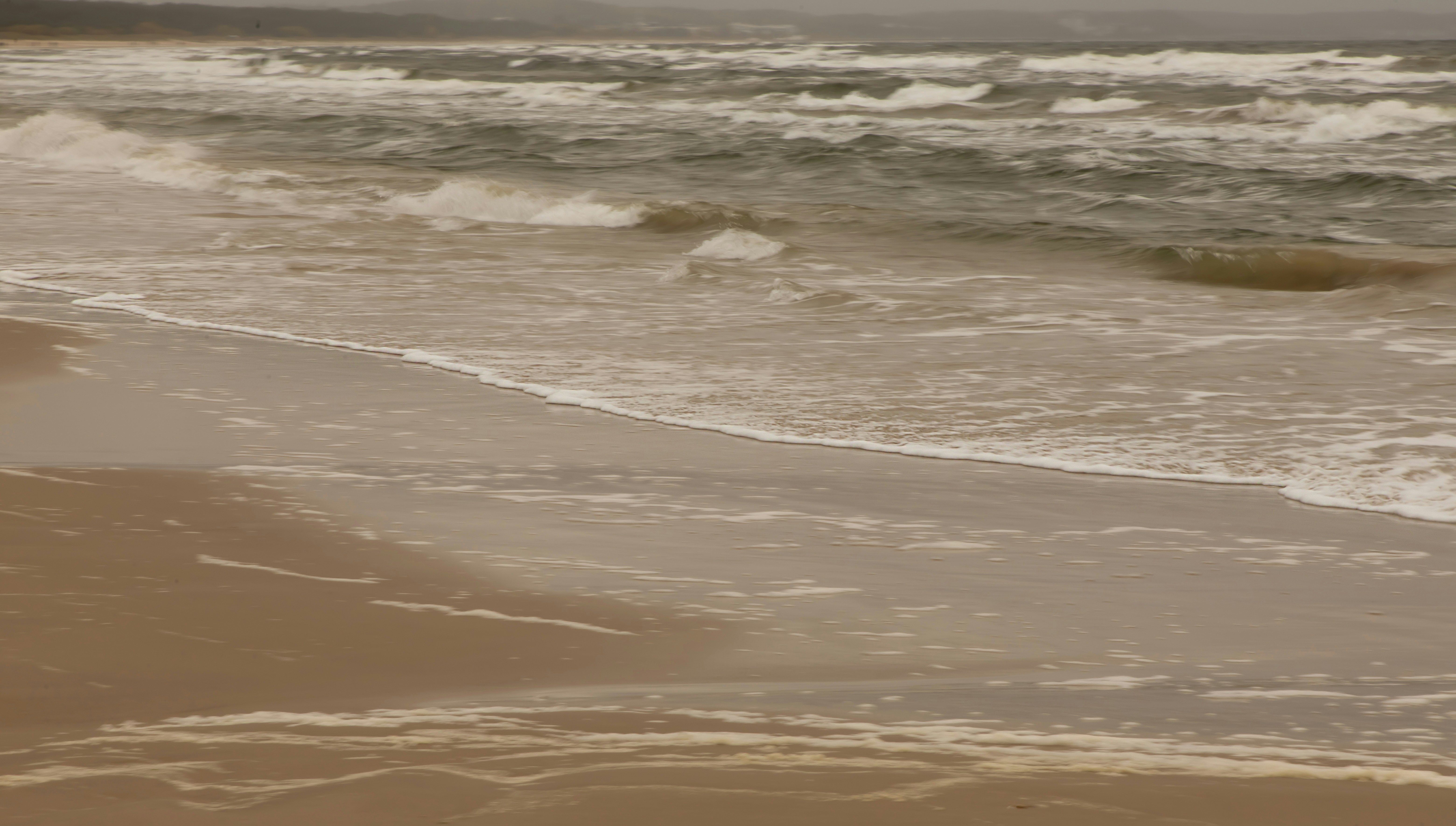 Waves gently lapping on a sandy beach.