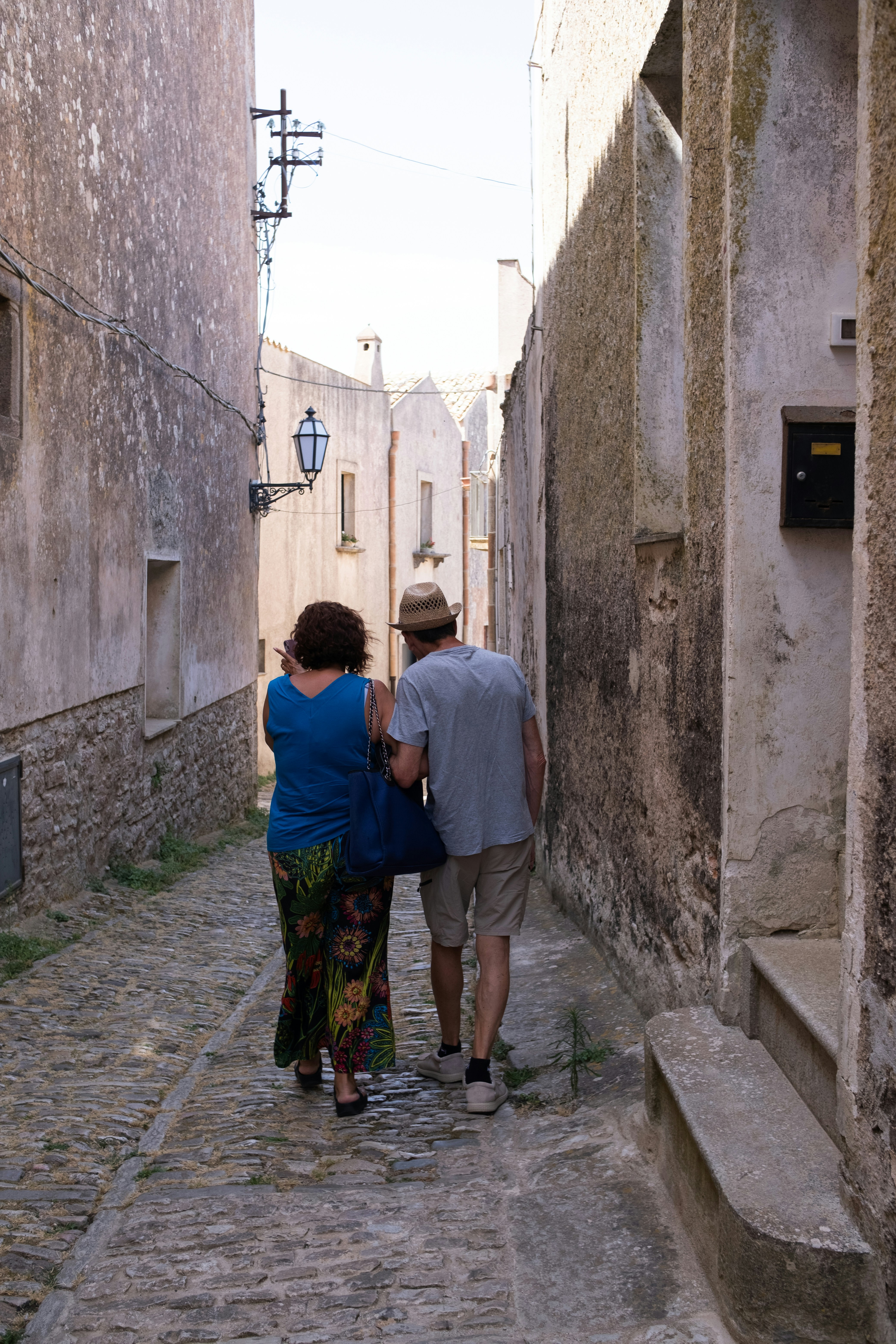 Couple walking down a narrow cobblestone street.