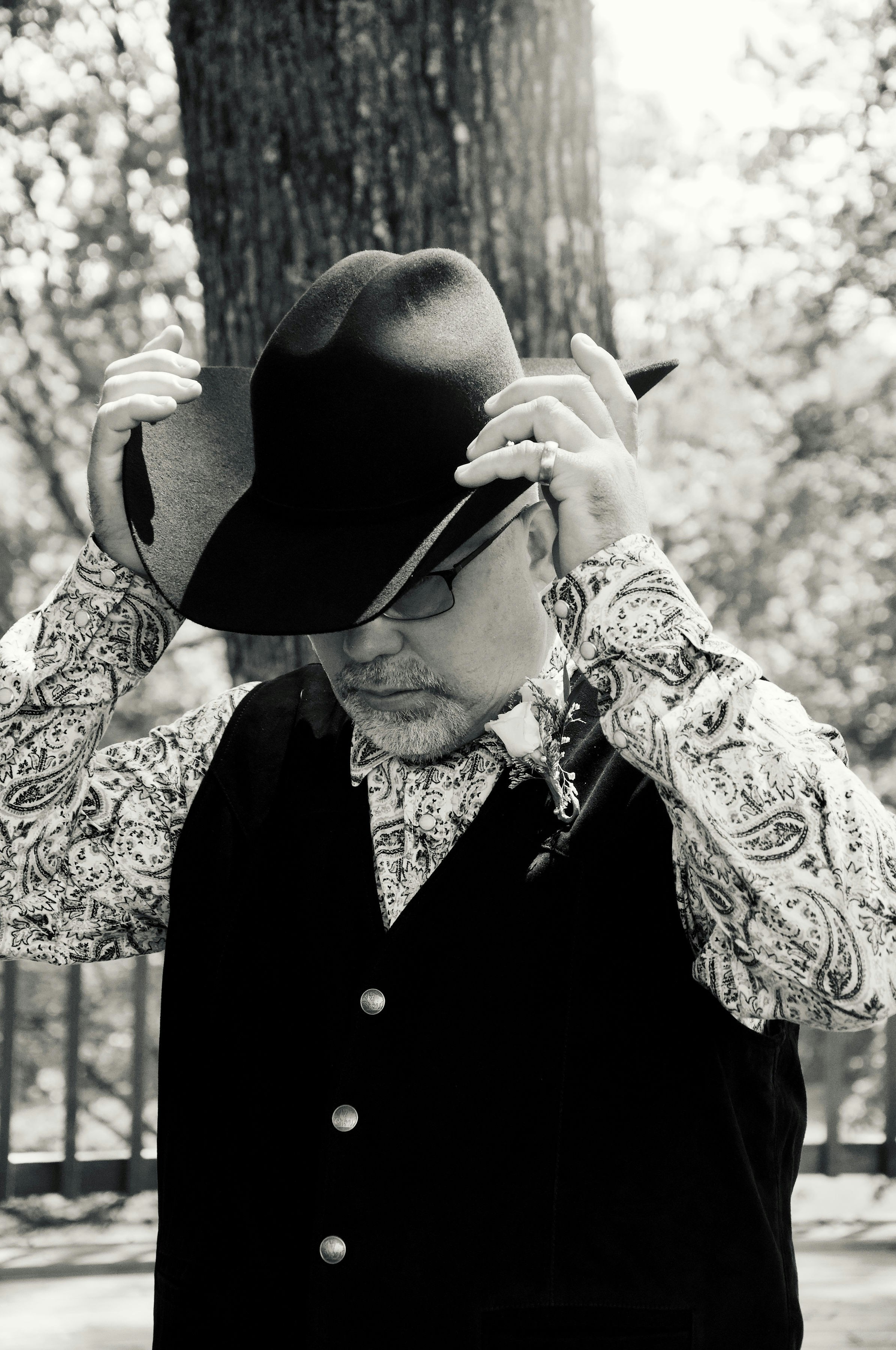 Man adjusting his cowboy hat outdoors