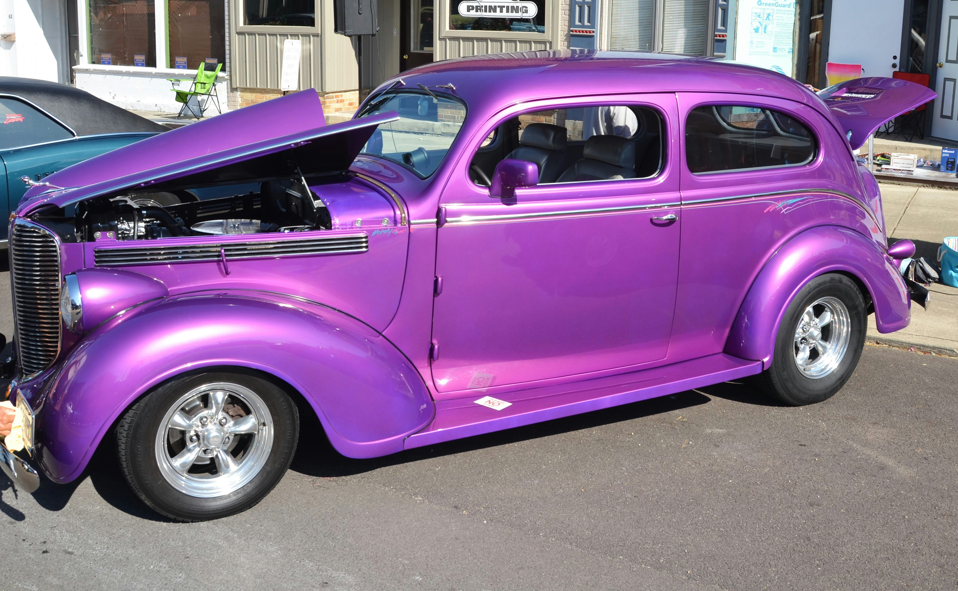 A vibrant purple vintage car with hood open