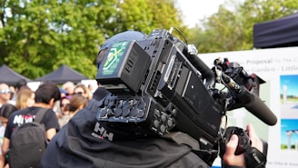 Professional camera filming an outdoor event with people.