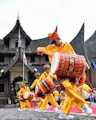 Men in yellow playing drums in front of traditional building