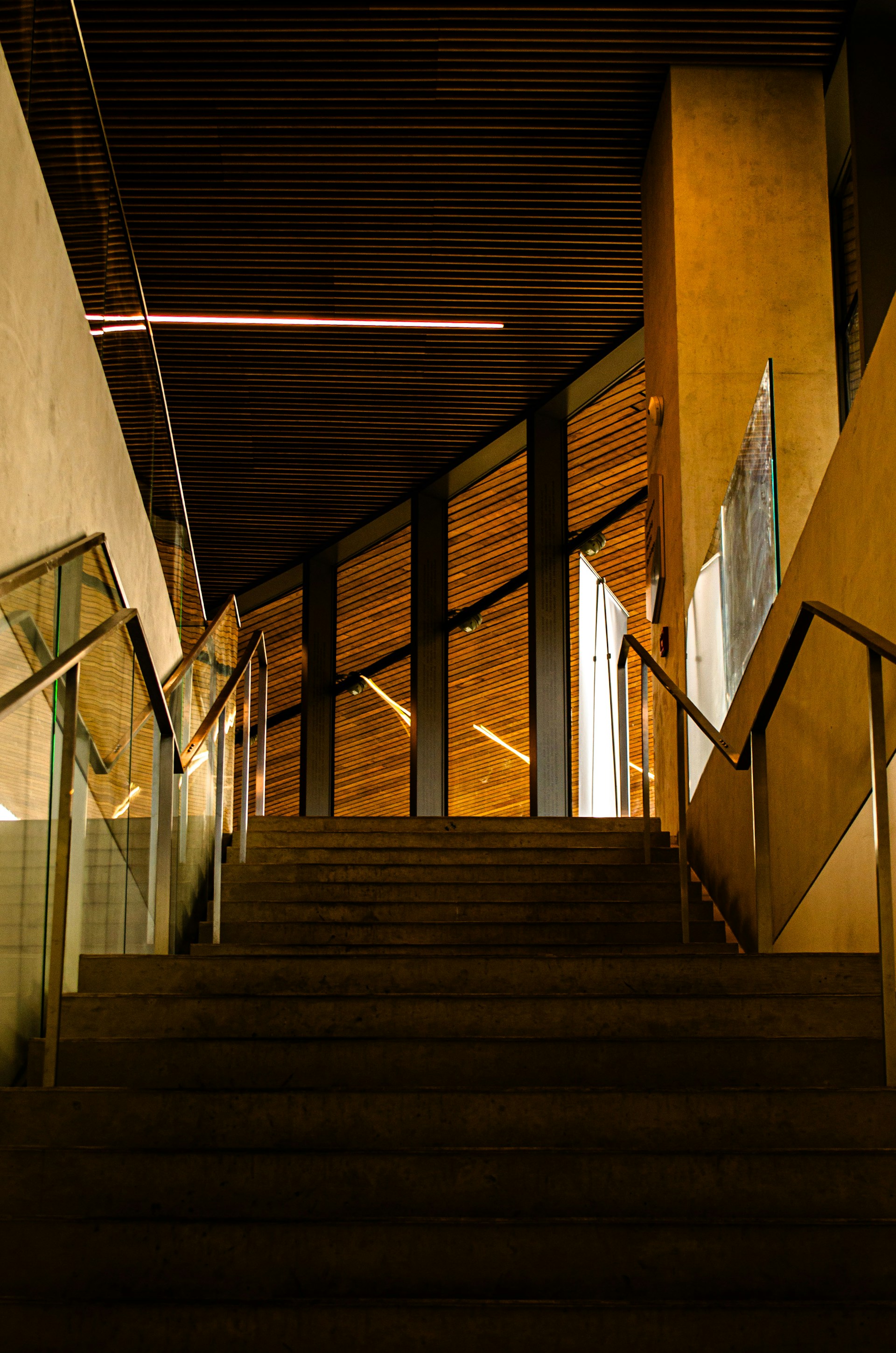 Modern staircase with wooden accents and glass railings.