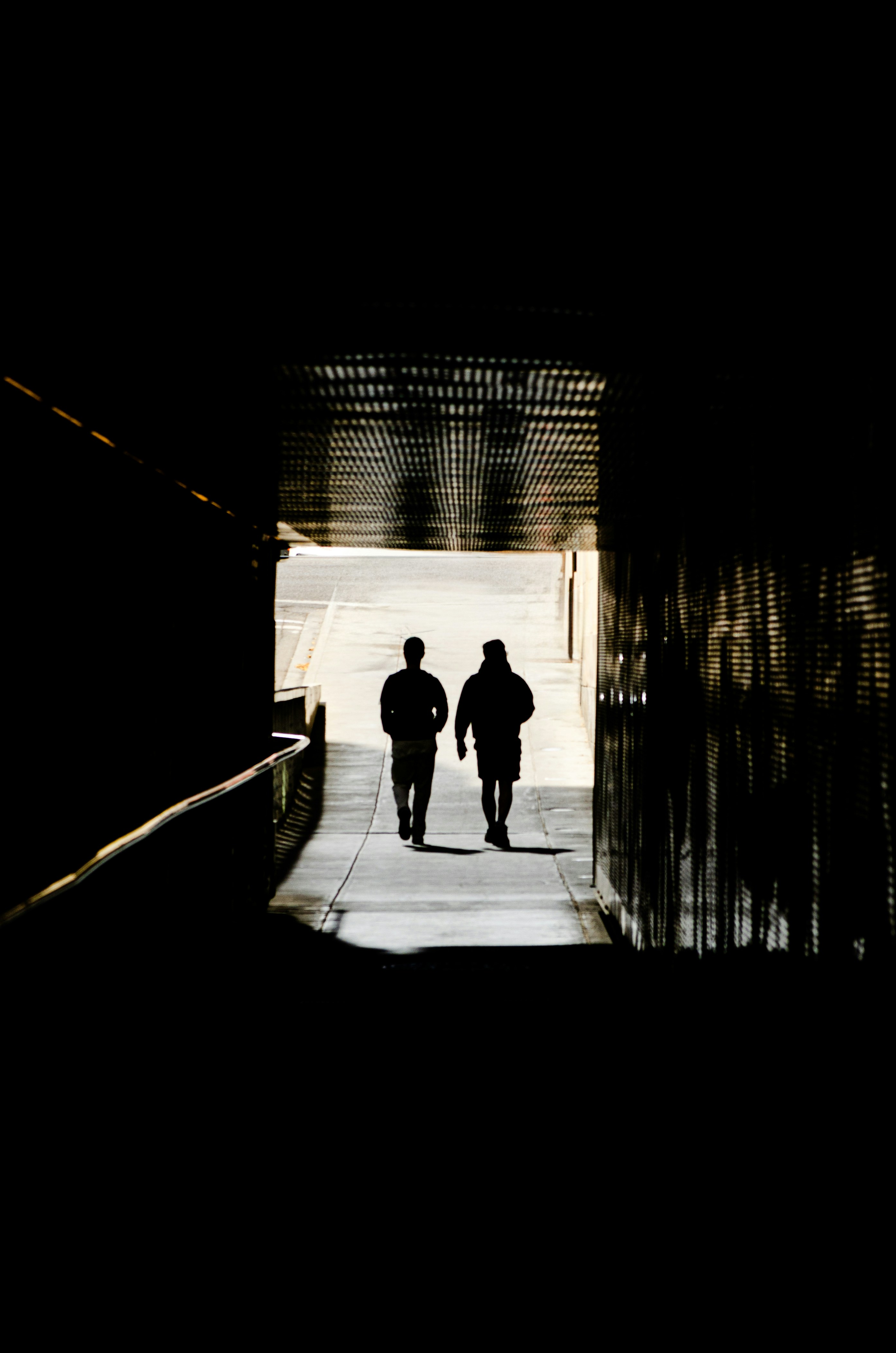 Two figures walk down a sunlit path.