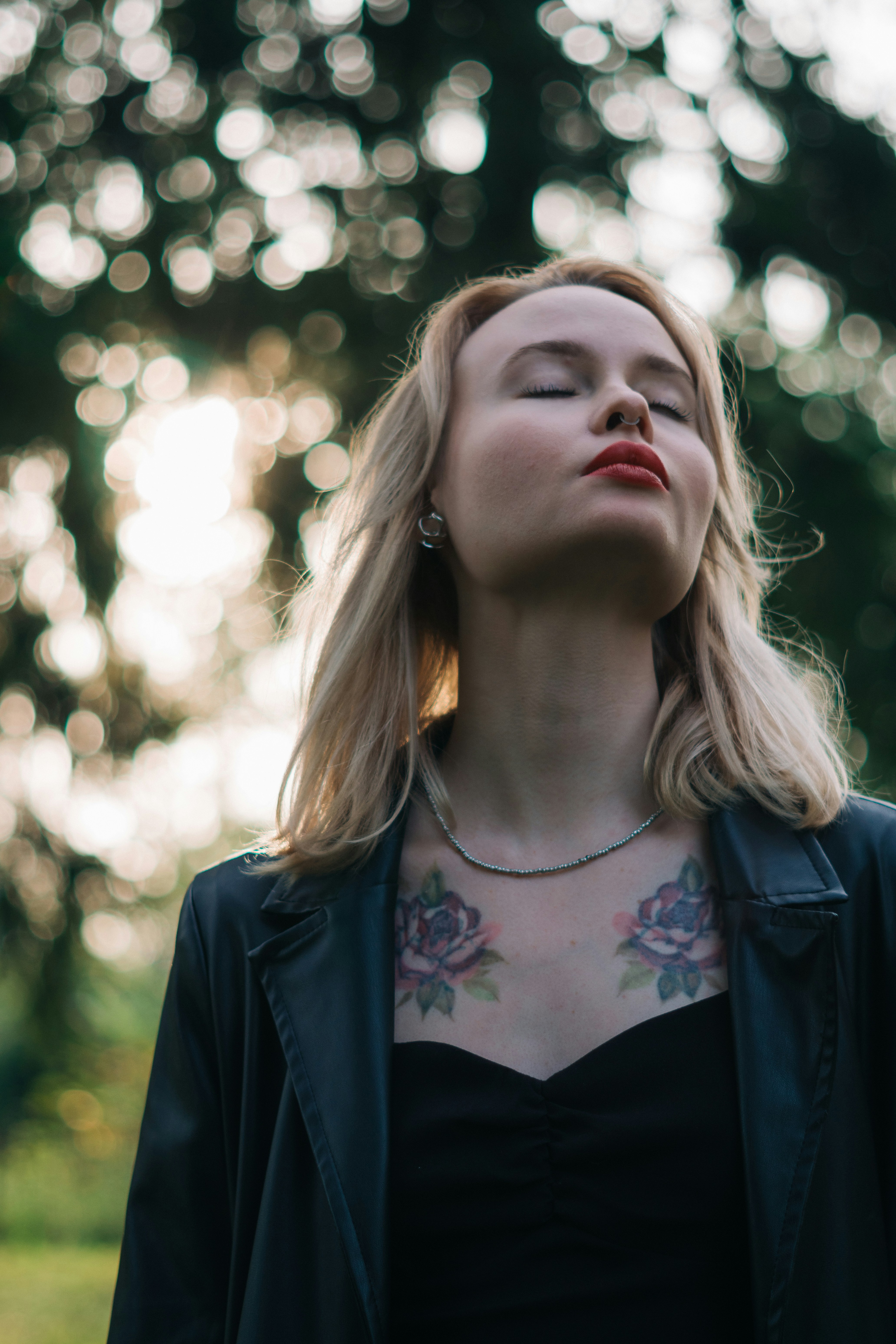 Woman with eyes closed and tattoos on chest