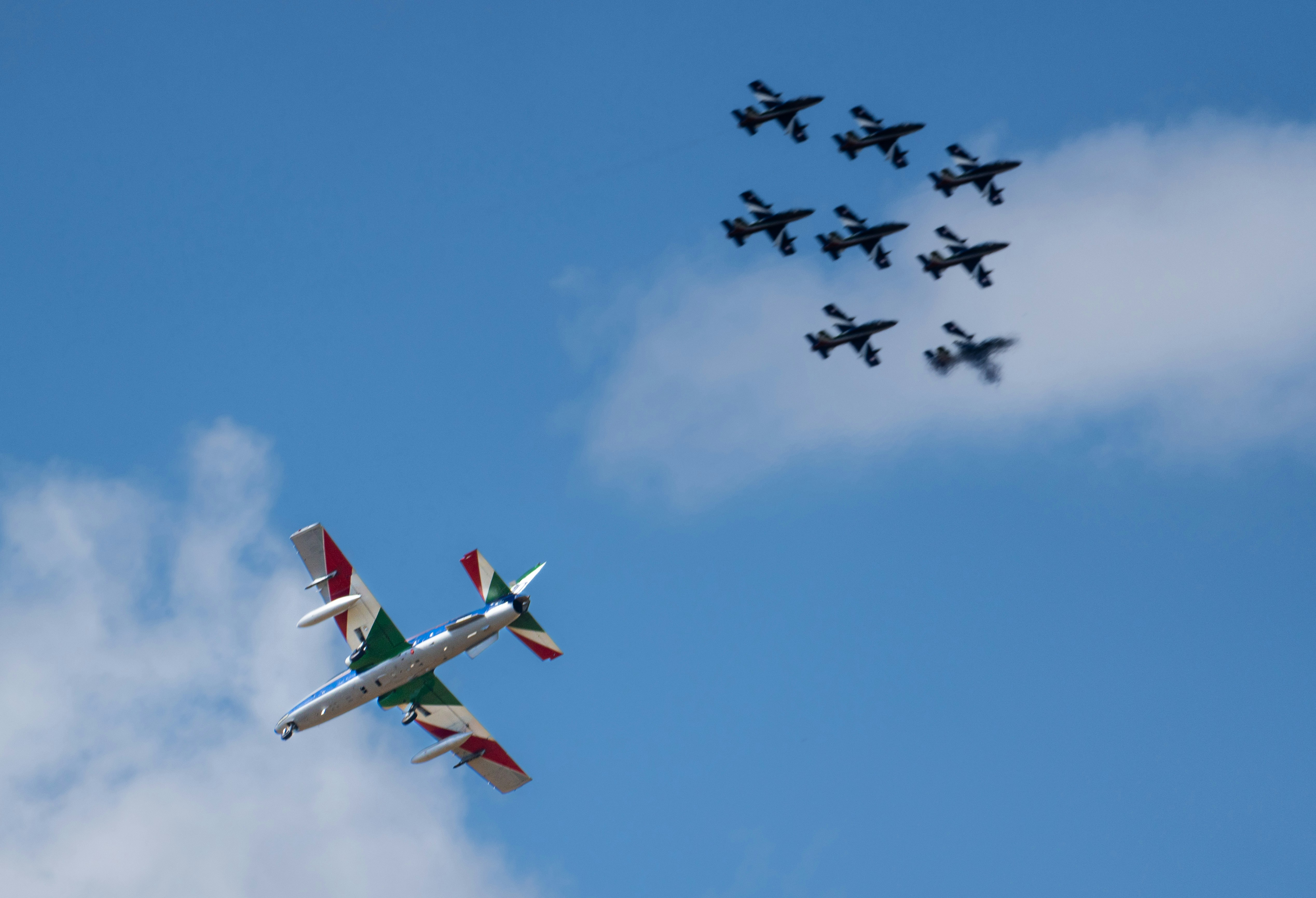 Nine jets fly in formation above one jet.