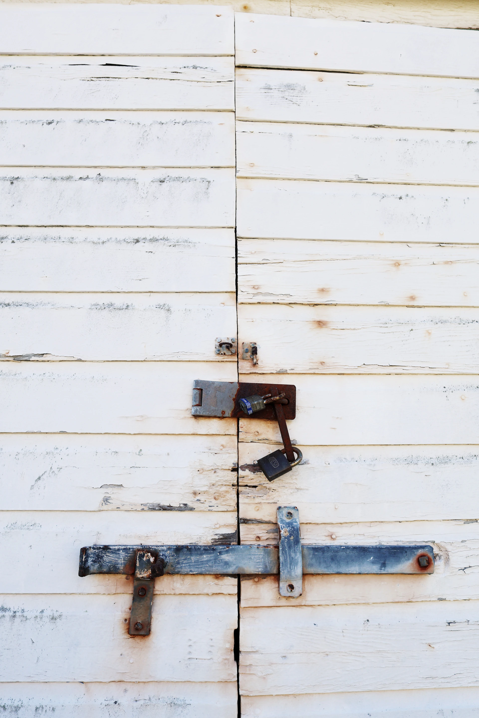 White wooden doors with rusty locks and latch