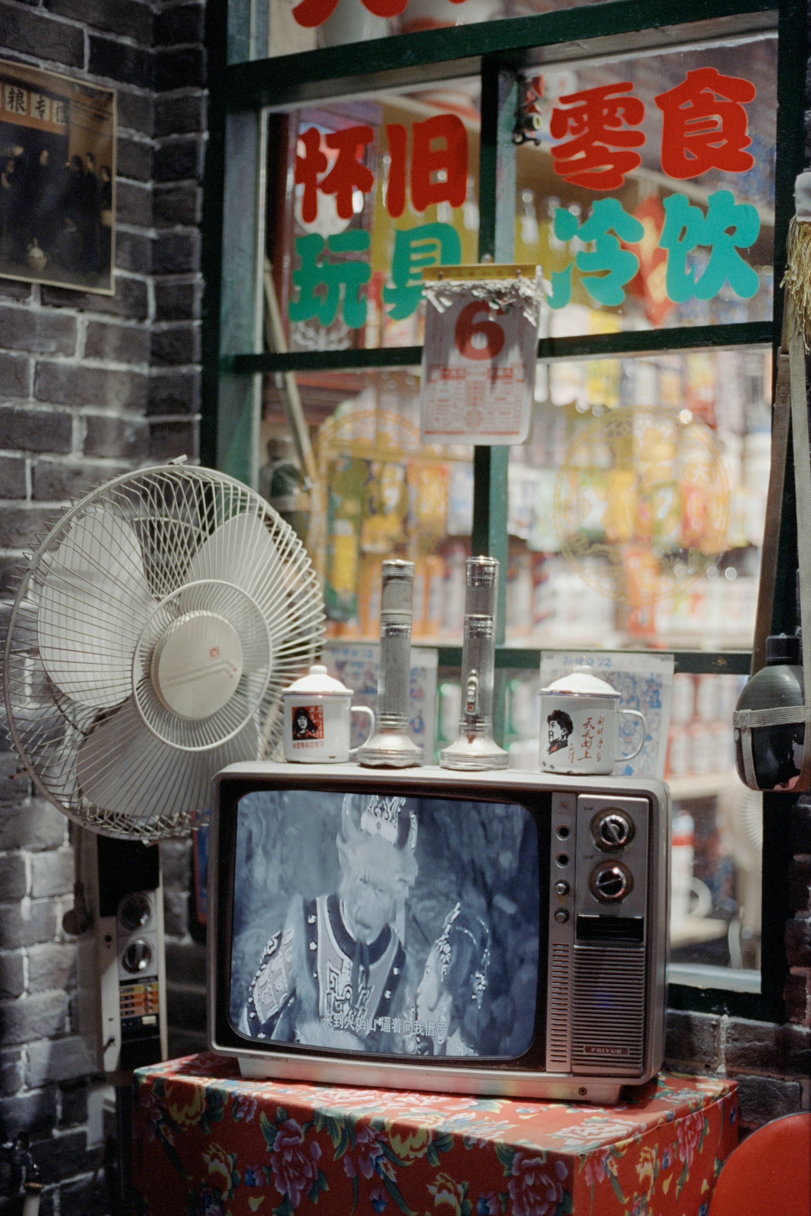 Vintage television set with a fan and mugs.