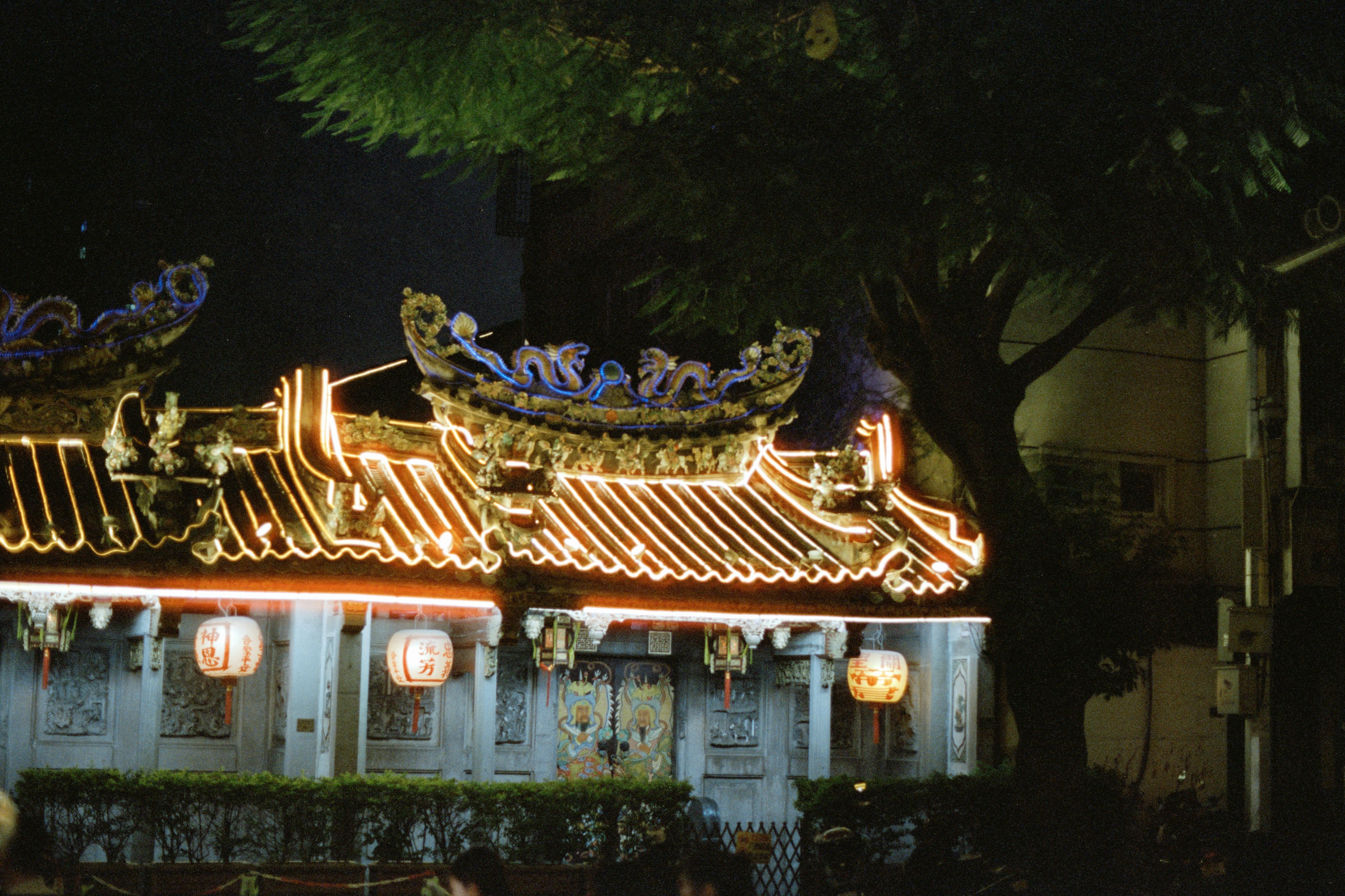 Ornate temple roof illuminated with festive lights at night.