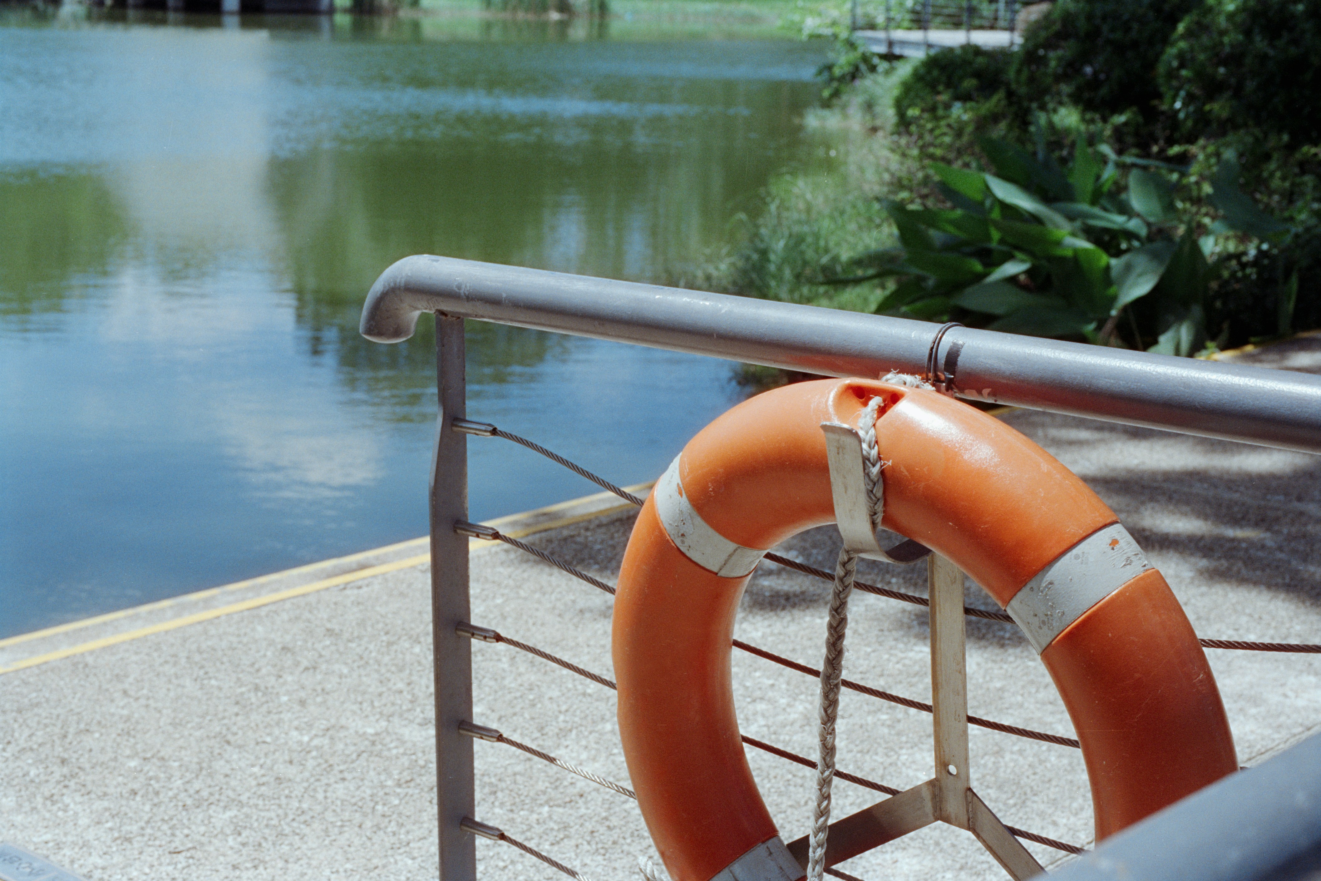 Orange life preserver hanging on railing by water