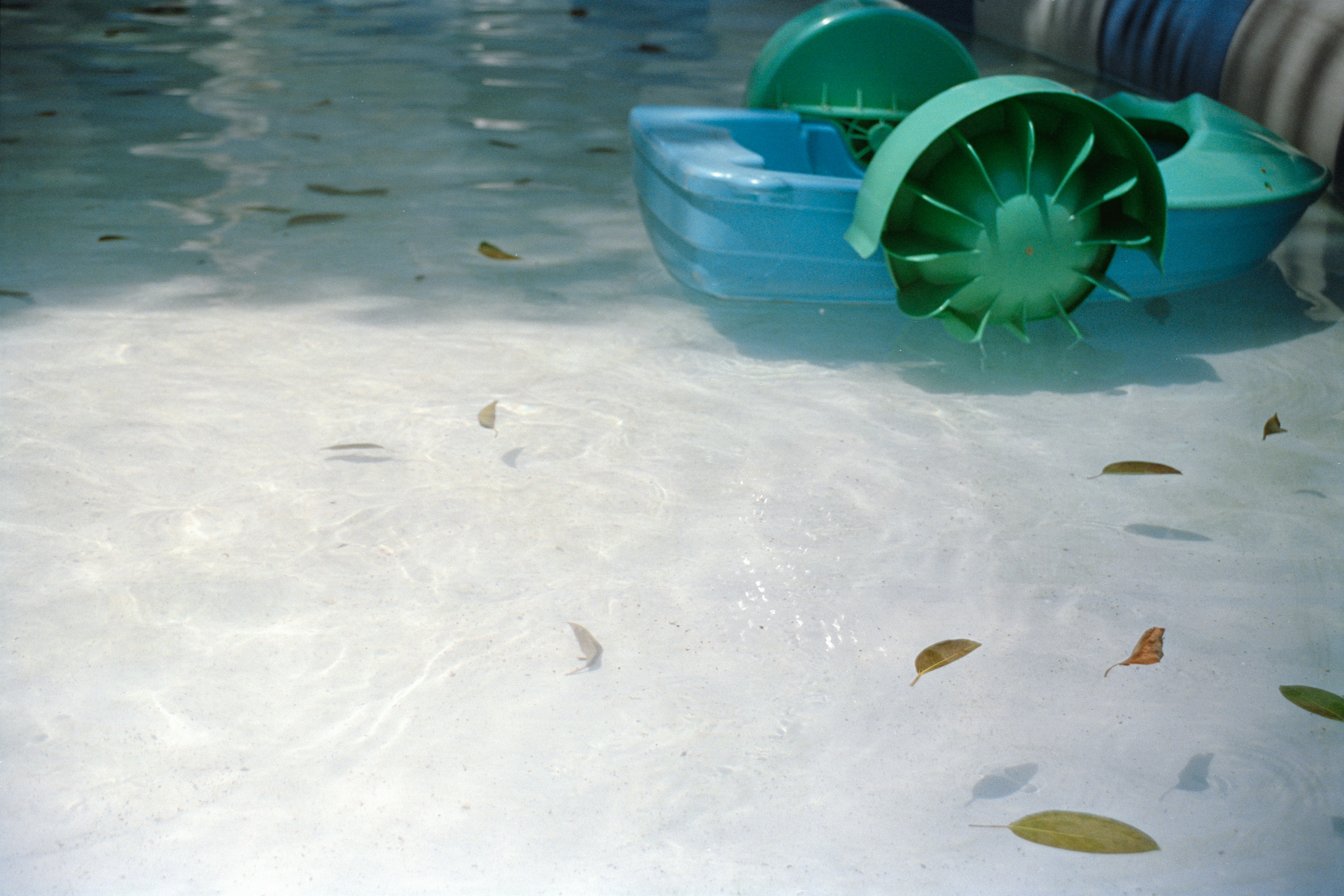 Turquoise paddle boat floats on clear water
