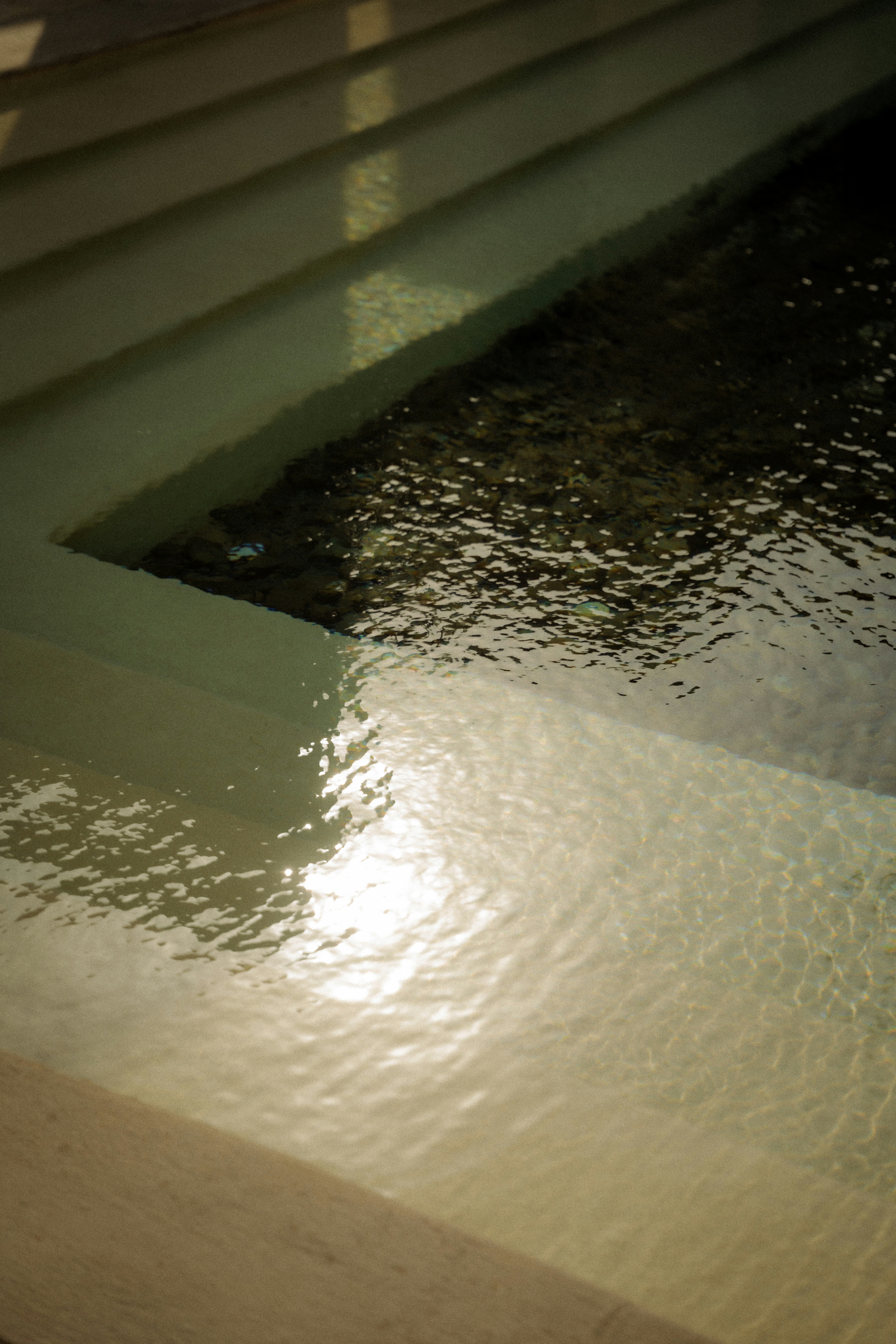 Sunlight reflects on rippling water in a modern pool.