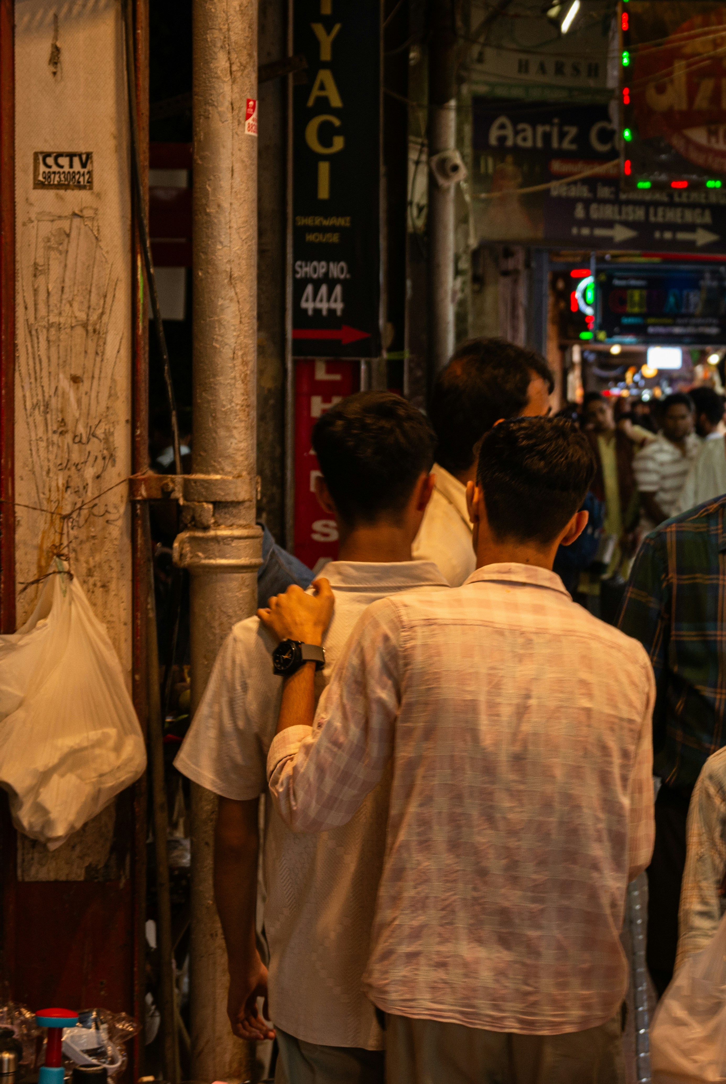 Deux hommes se tiennent dans une rue animée la nuit.