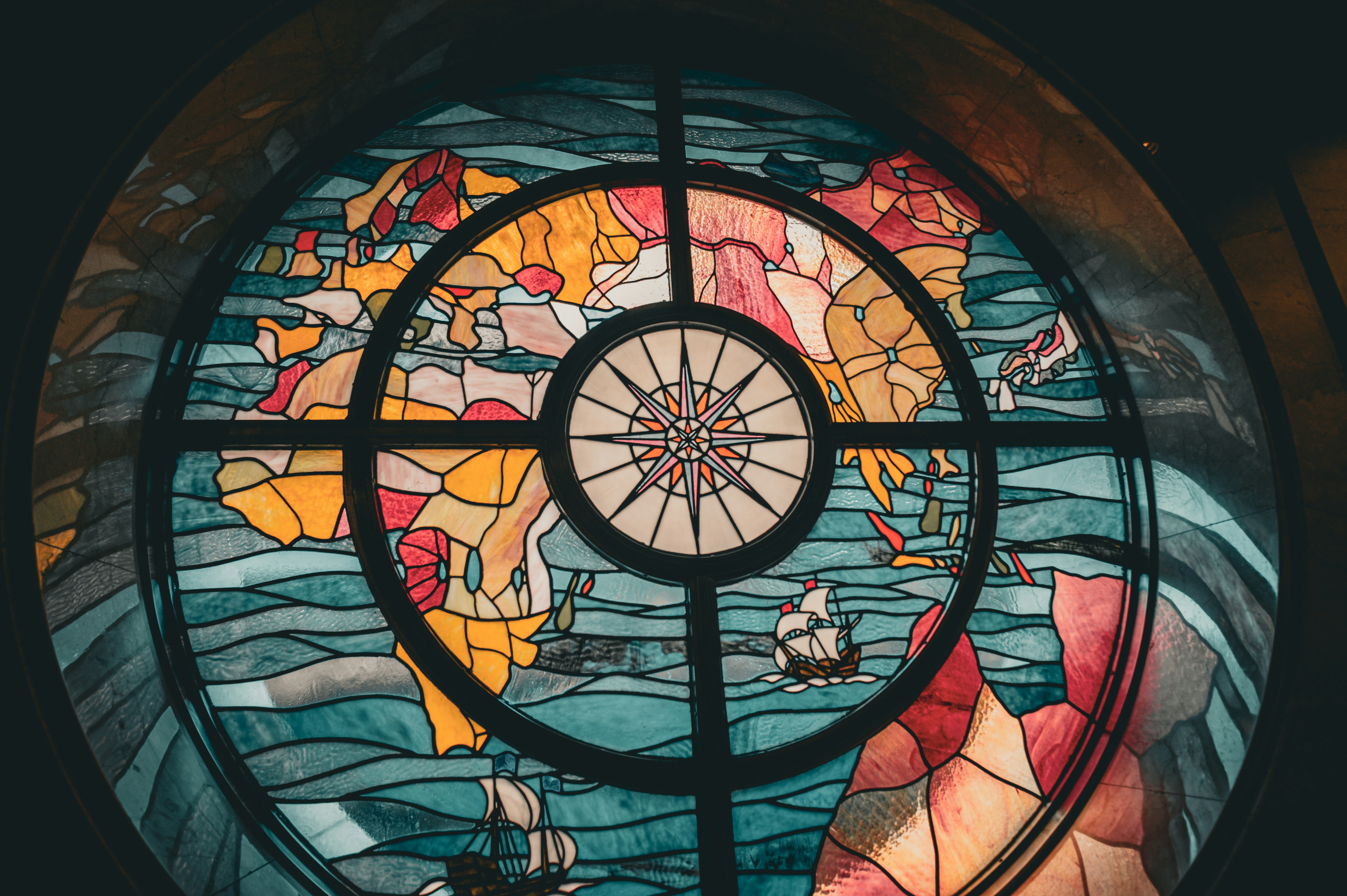 Stained glass window with a world map and compass.