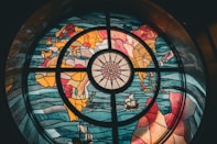 Stained glass window with a world map and compass.