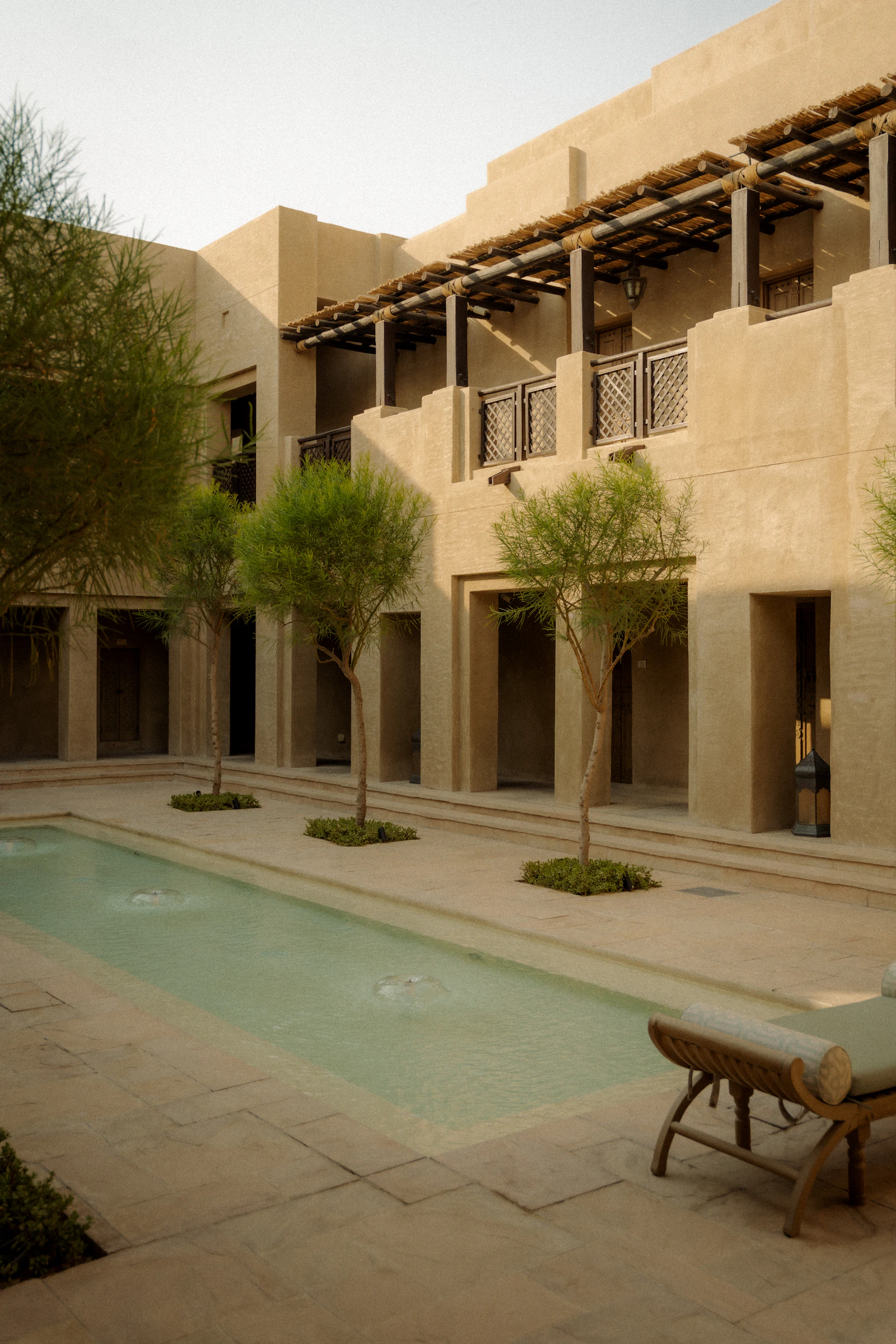 Cour contemporaine plantée d'arbres, avec bassin et façades claires