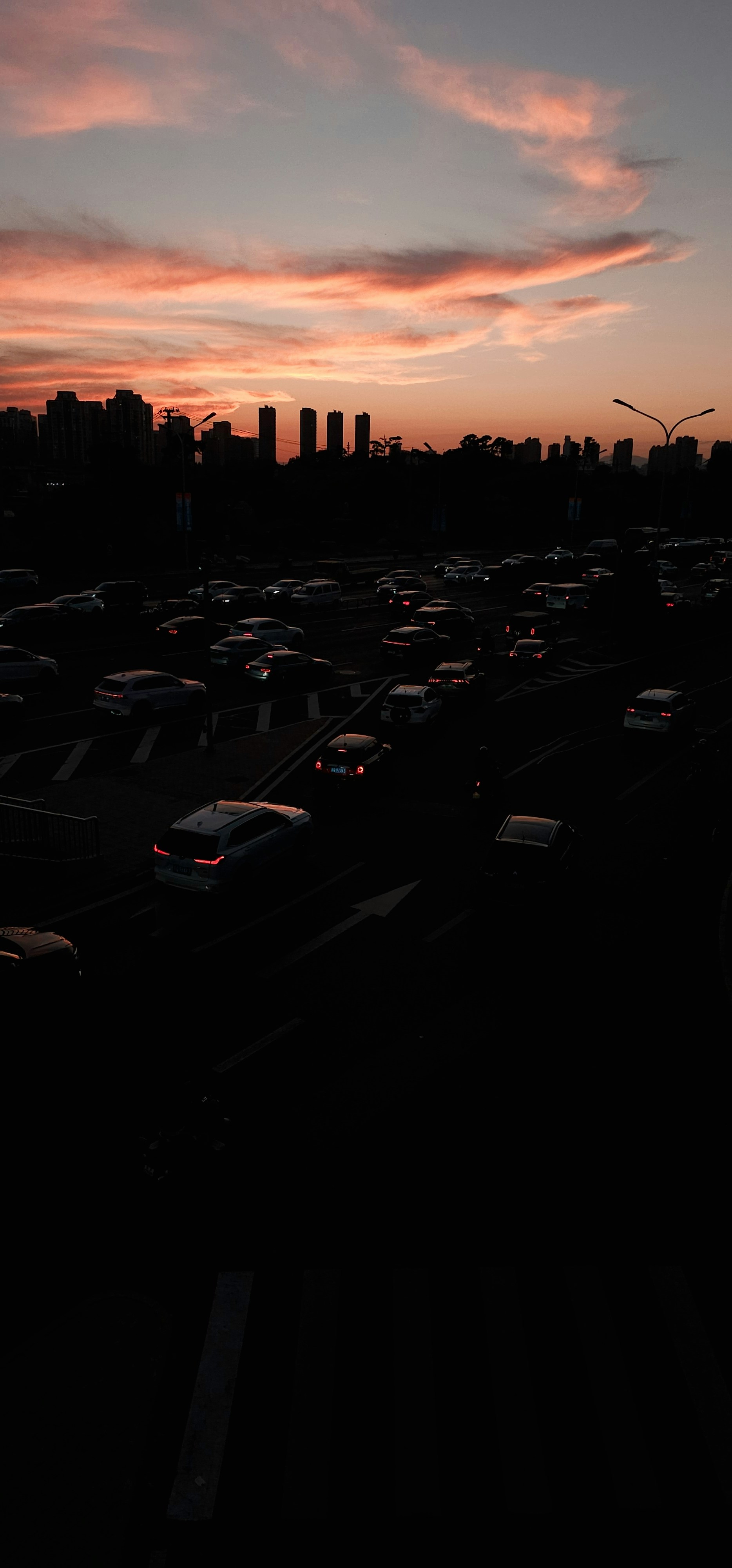 Traffic jam on highway at sunset with city skyline.