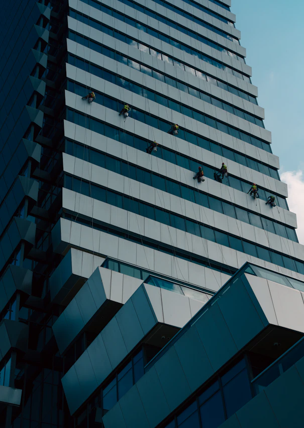 Window cleaners work on a modern skyscraper facade.